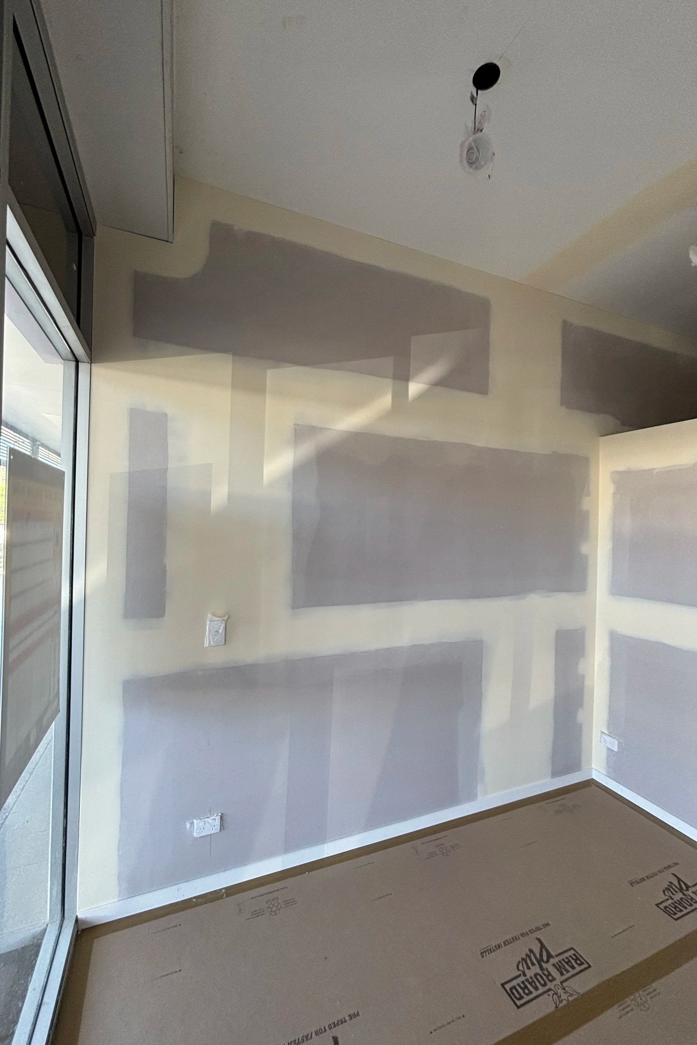 Empty room with a glass door, painted walls, electrical outlets, and an unfinished ceiling with visible wiring and holes.