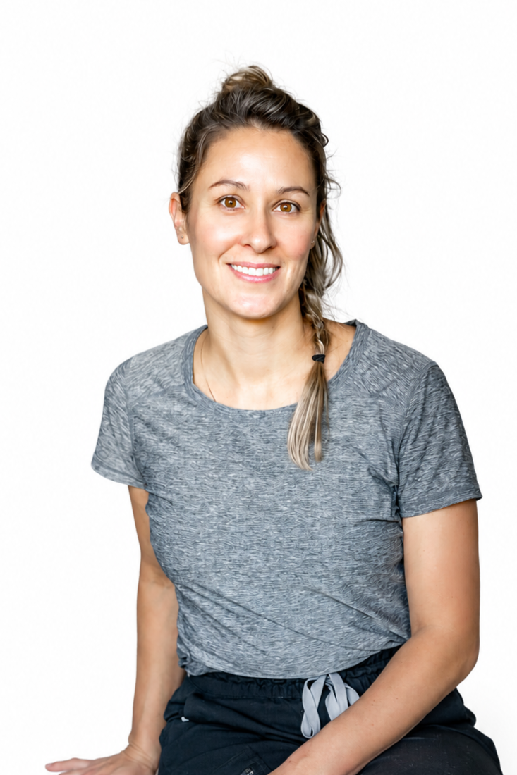 Une femme souriante, portant un t-shirt gris et un pantalon noir, avec un hair en queue de cheval, assise contre un fond blanc.