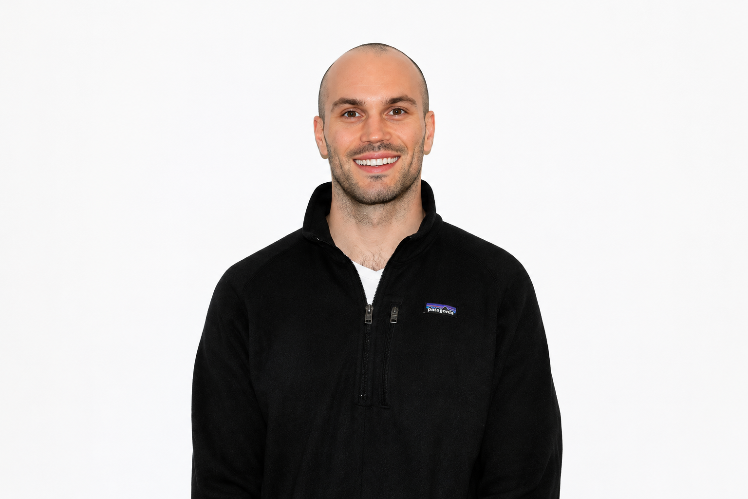 Homme souriant portant une veste noire Patagonia, fond blanc