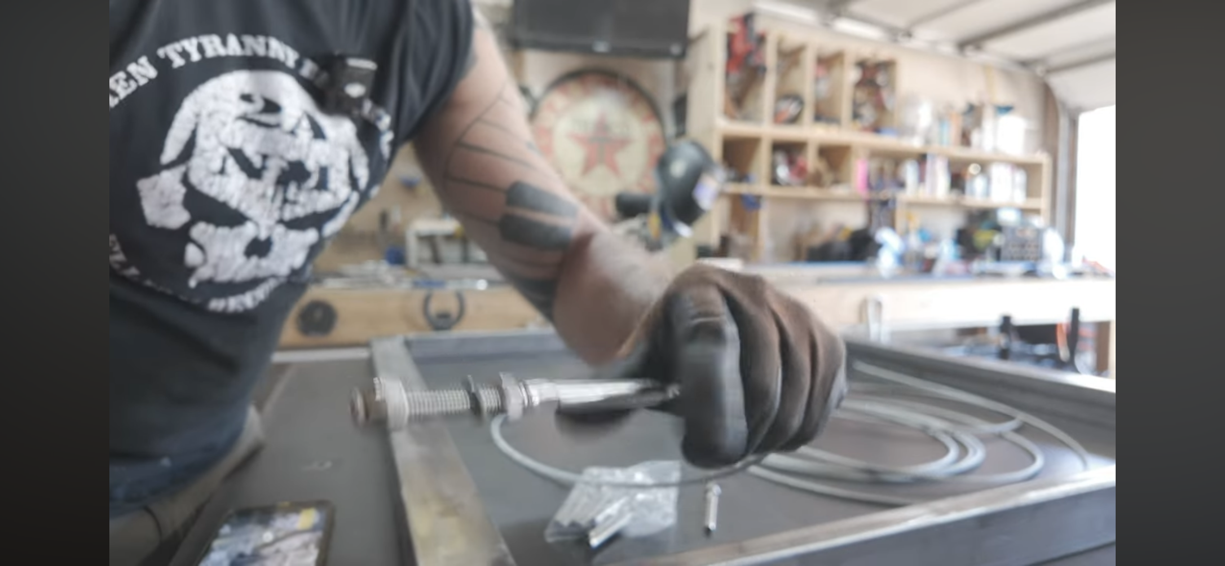 A person working in a woodworking workshop, with shelves filled with tools and supplies in the background.