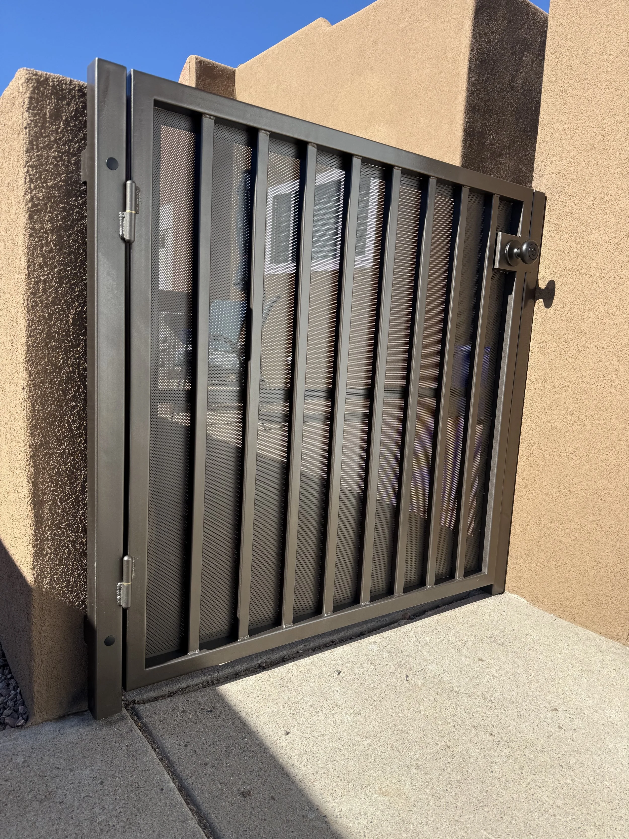 Custom metal privacy gate with vertical bars and perforated panel.