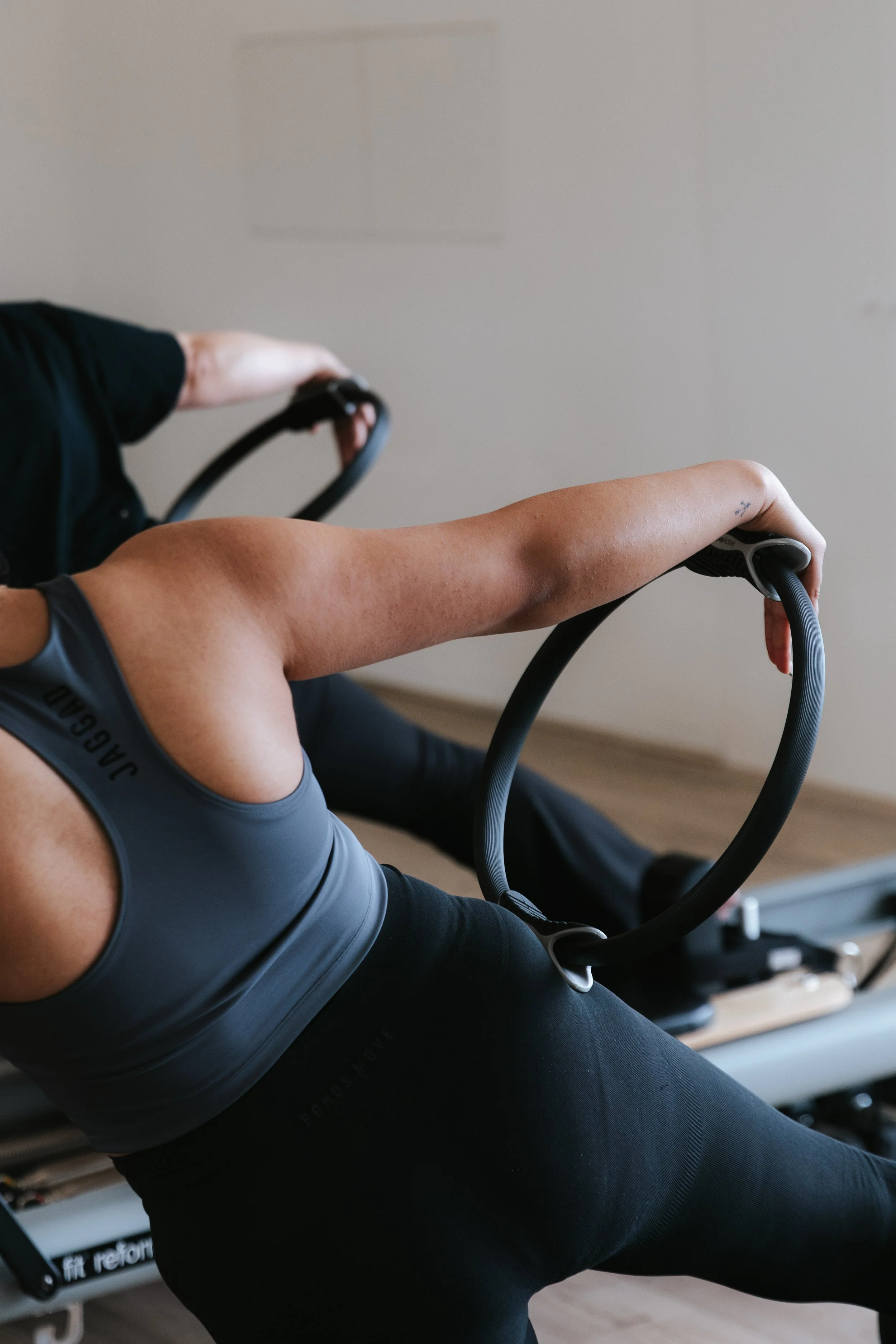 Sage Pilates Brunswick West © | Person exercising on a rowing machine in a gym, focusing on their arm and torso muscles.