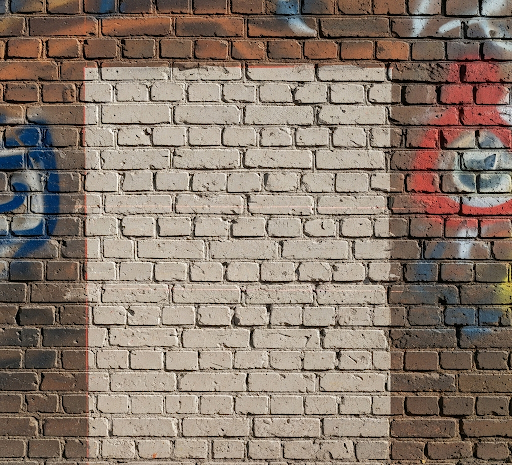 Brick wall with partially painted white rectangle and some graffiti around it.