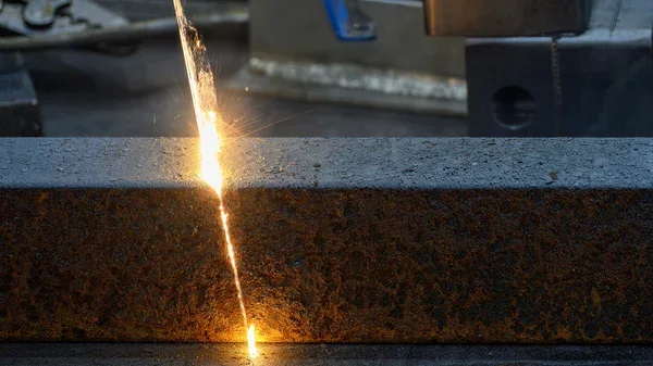 A close-up view of a metalwork process showing sparks flying off a heated metal piece.