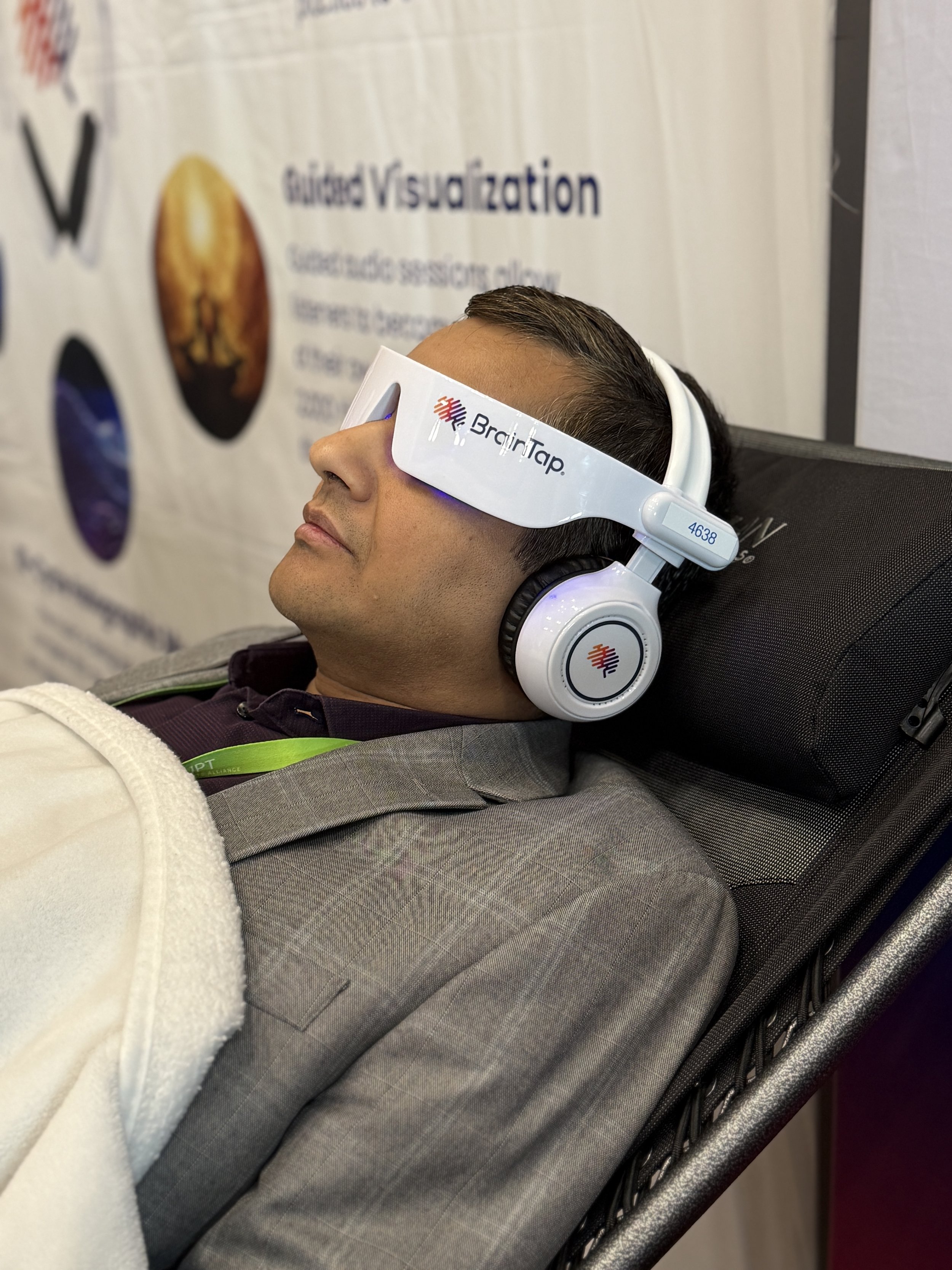 Person relaxing during a BrainTap neuroacoustic wellness session using a BrainTap headset to support stress reduction, focus, relaxation, and sleep wellness.