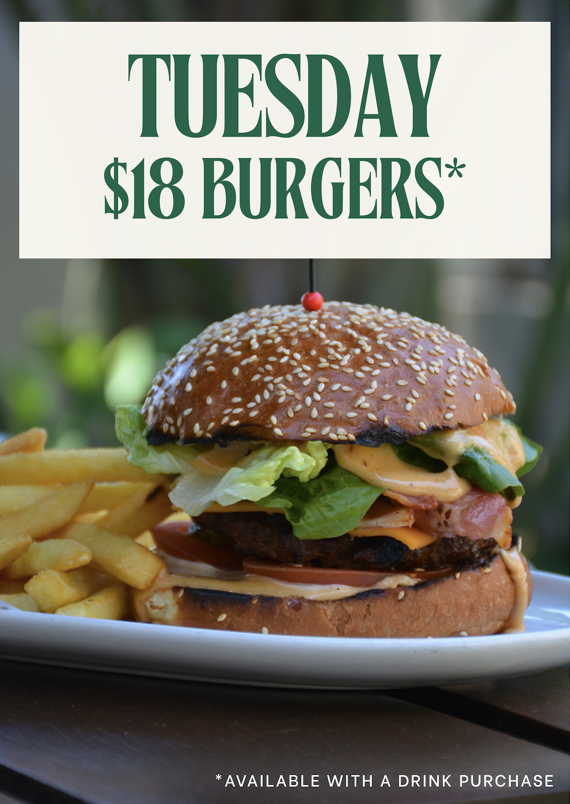 A promotional sign advertising $18 burgers on Tuesday, featuring a close-up of a burger with fries, lettuce, cheese, bacon, and sesame seed bun. Text includes 'Tuesday $18 Burgers*' and '*Available with a drink purchase'.