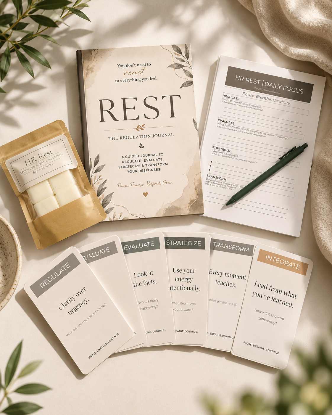 A workspace with a regulation journal titled 'Rest,' a set of cards with instructions for regulating, evaluating, strategizing, transforming, and integrating responses, a paper with prompts about HR rest and daily focus, a pen, a small bag of wax melts labeled 'HR Rest,' a bowl of salt, and some greenery in the background.
