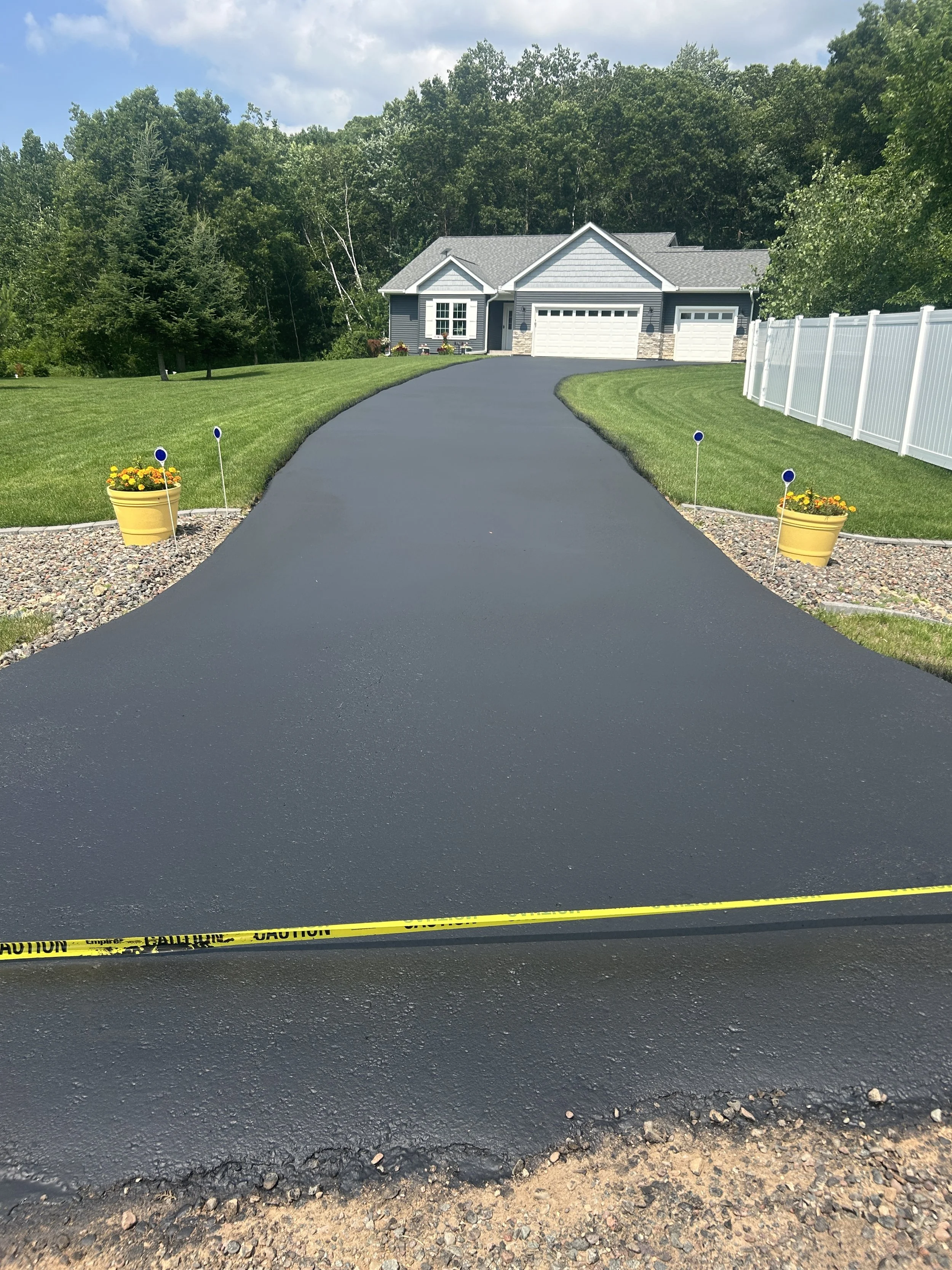 A fresh asphalt sealcoat with superior crack filling on a residential driveway in Minnesota. The asphalt is perfectly edged and prepped by 7 County Sealcoating professionals.