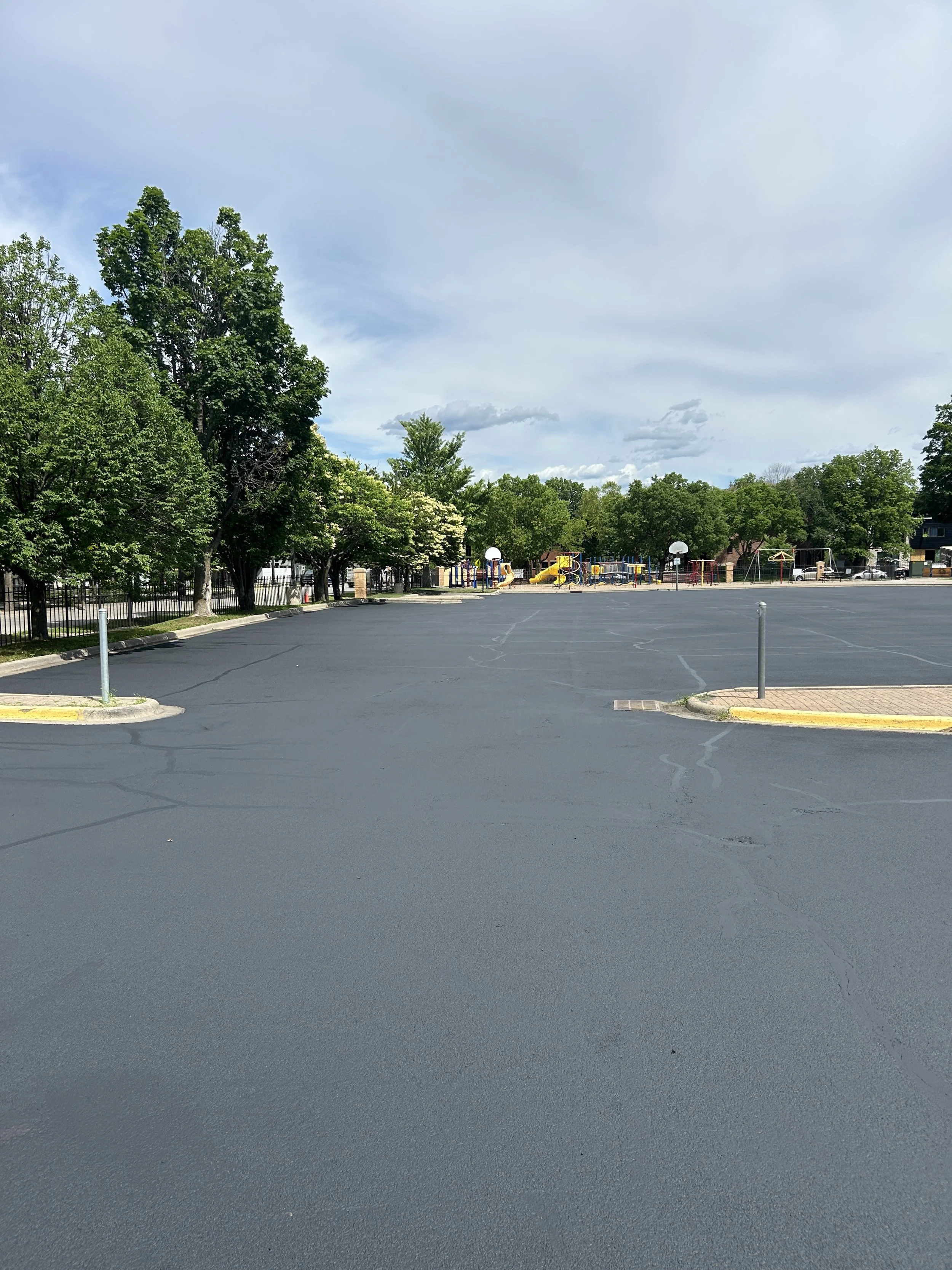A freshly sealcoated parking lot at St Bartholomew Catholic Church in Wayzata, Minnesota, pictured prior to final line striping. Expert asphalt prep, cleaning, patching, crack filling, and sealcoating services provided by 7 County Sealcoating.