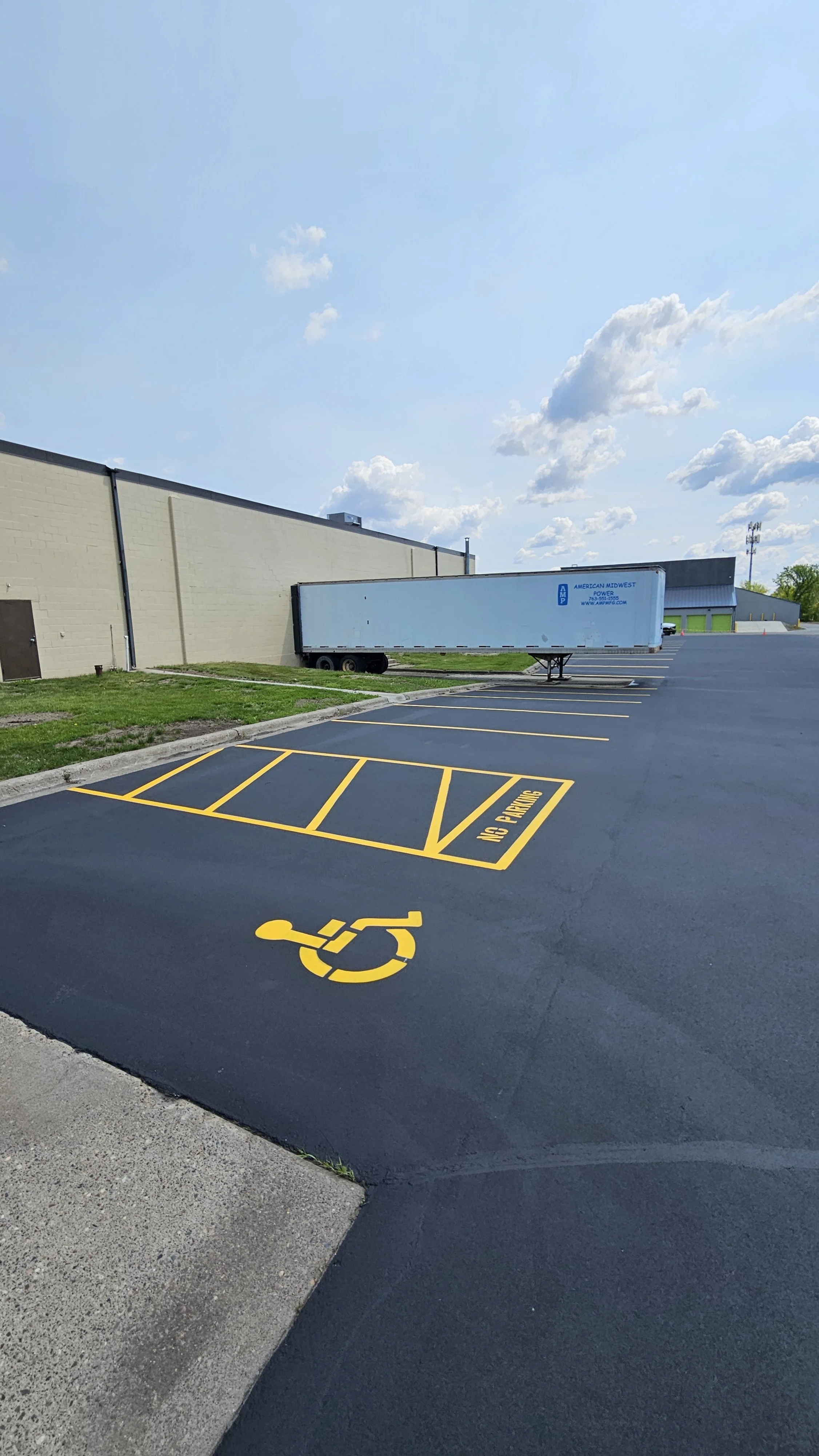 An expert sealcoat application on a commercial parking lot by 7 County Sealcoating, featuring new accessible parking space striping, smooth hot rubber crack filling, and crisp borders.
