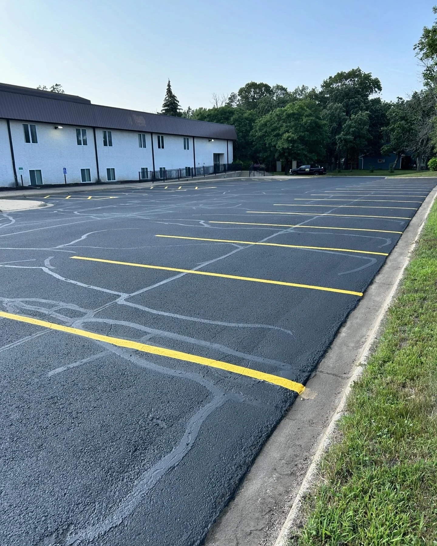 A freshly sealcoated and striped commercial parking lot of a church in Coon Rapids, Minnesota, demonstrating professional asphalt maintenance by 7 County Sealcoating.