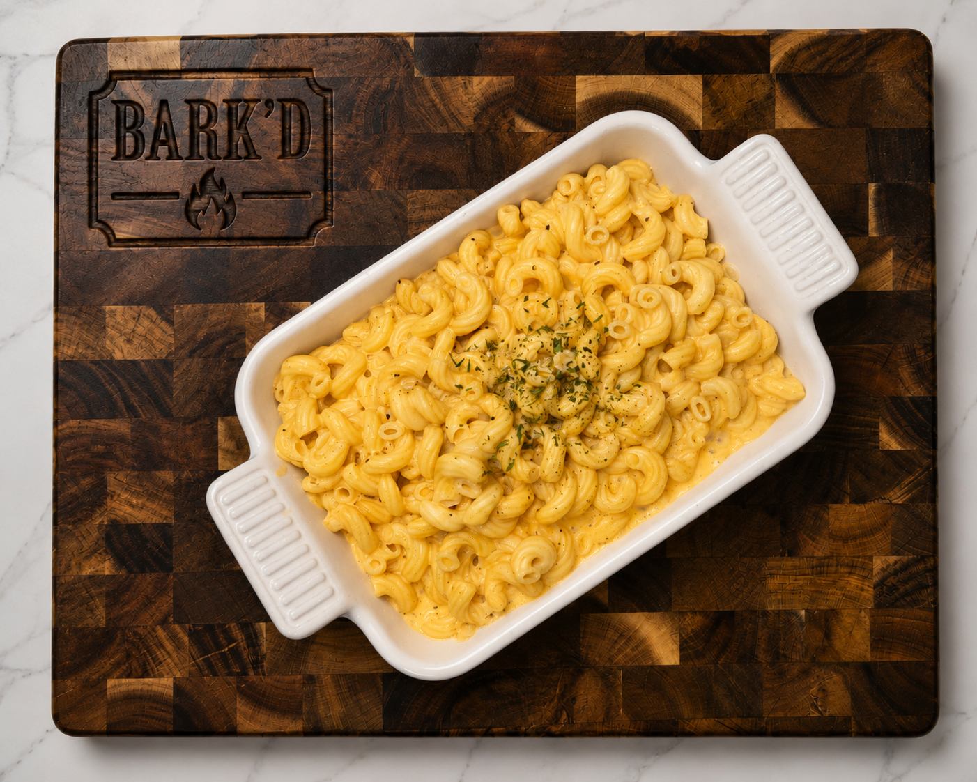 Creamy macaroni and cheese in a white baking dish on a dark wooden cutting board.