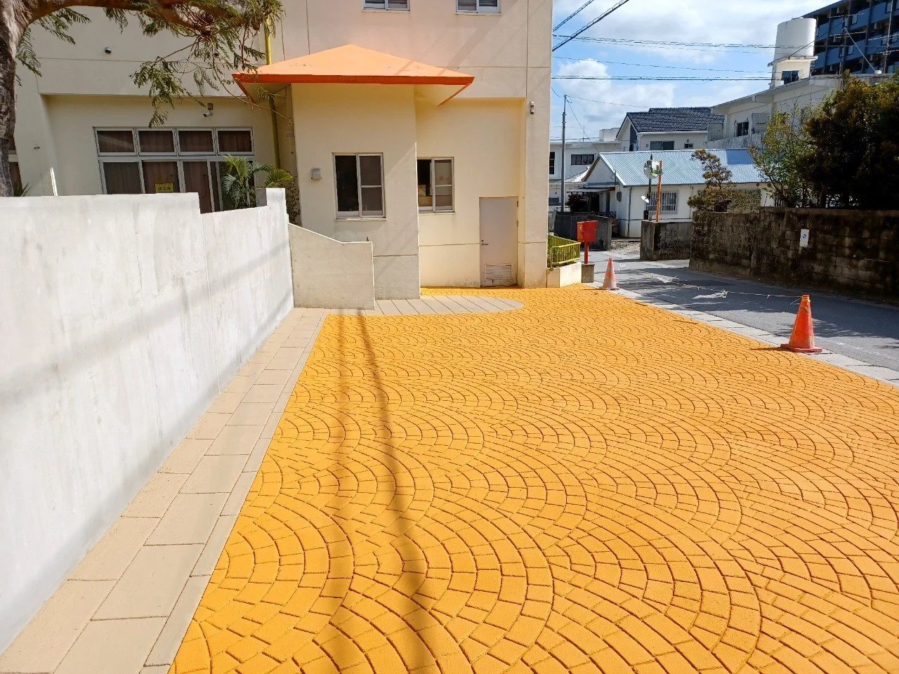 黄色のレンガ舗装の駐車場と白い建物、コーンと電線が見える都市景観