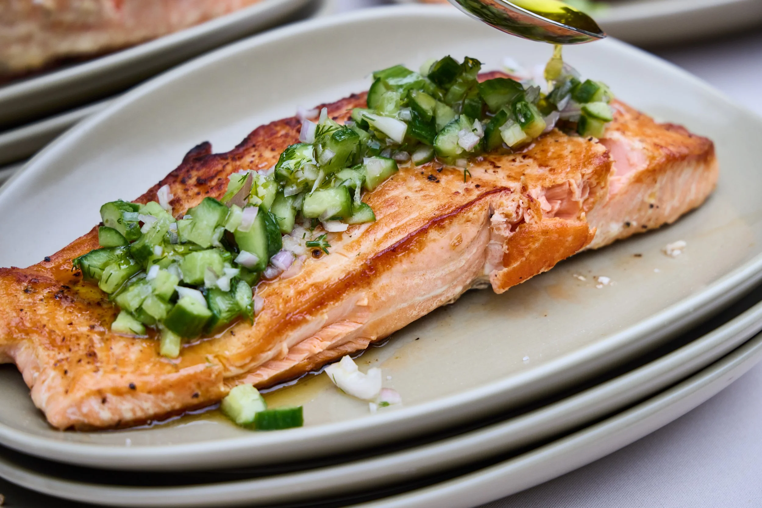 Grilled line caught Bolinas salmon fillet topped with chopped cucumbers, onions, and herbs, with a drizzle of olive oil at Debonair Events reception.