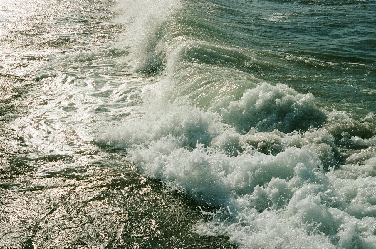 Waves crashing and splashing in the ocean with sunlight reflecting off the water surface.