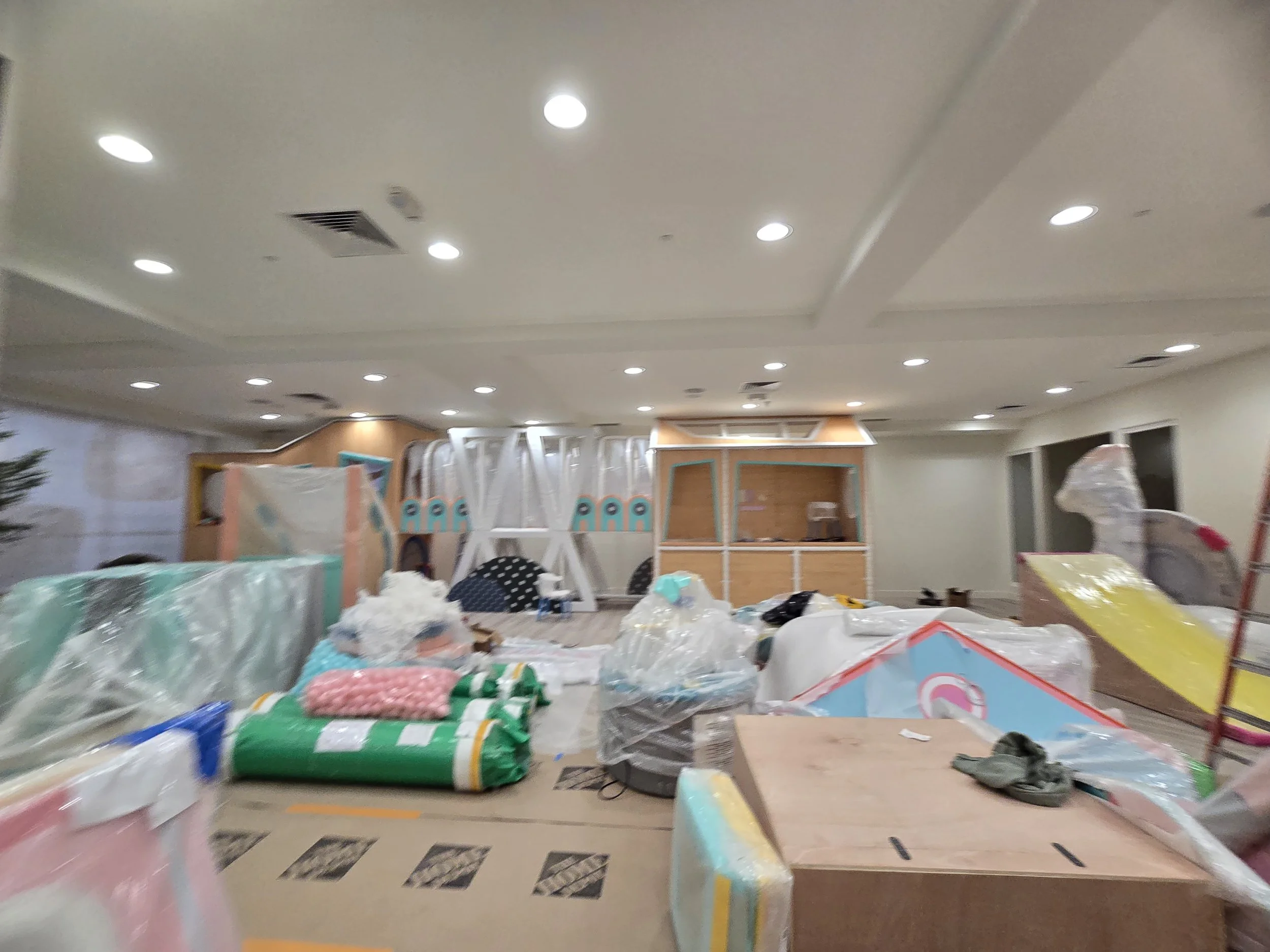 Room filled with various colorful items and furniture, partially covered with plastic, possibly a store or storage space.