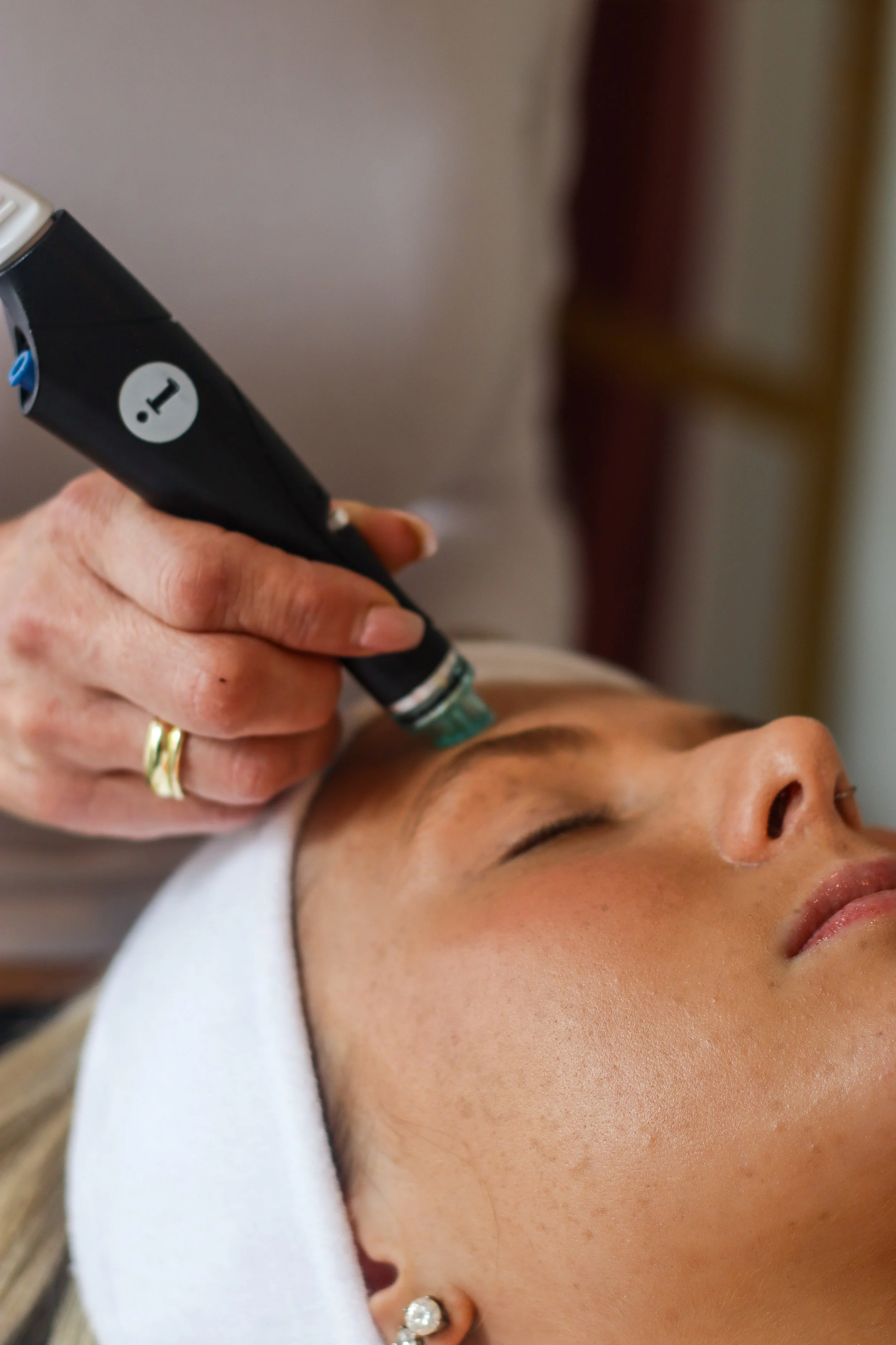 A person receiving a facial treatment with a handheld device on their forehead at a spa or skincare clinic.