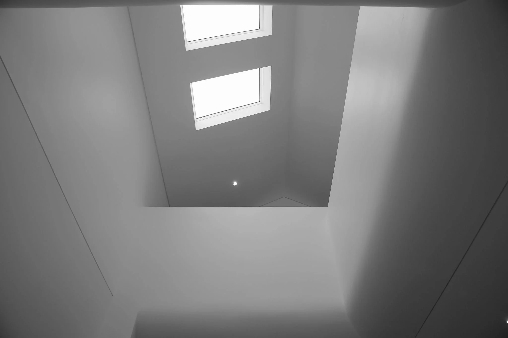 Looking up at a rectangular skylight in a plain white ceiling, with a small recessed light below.