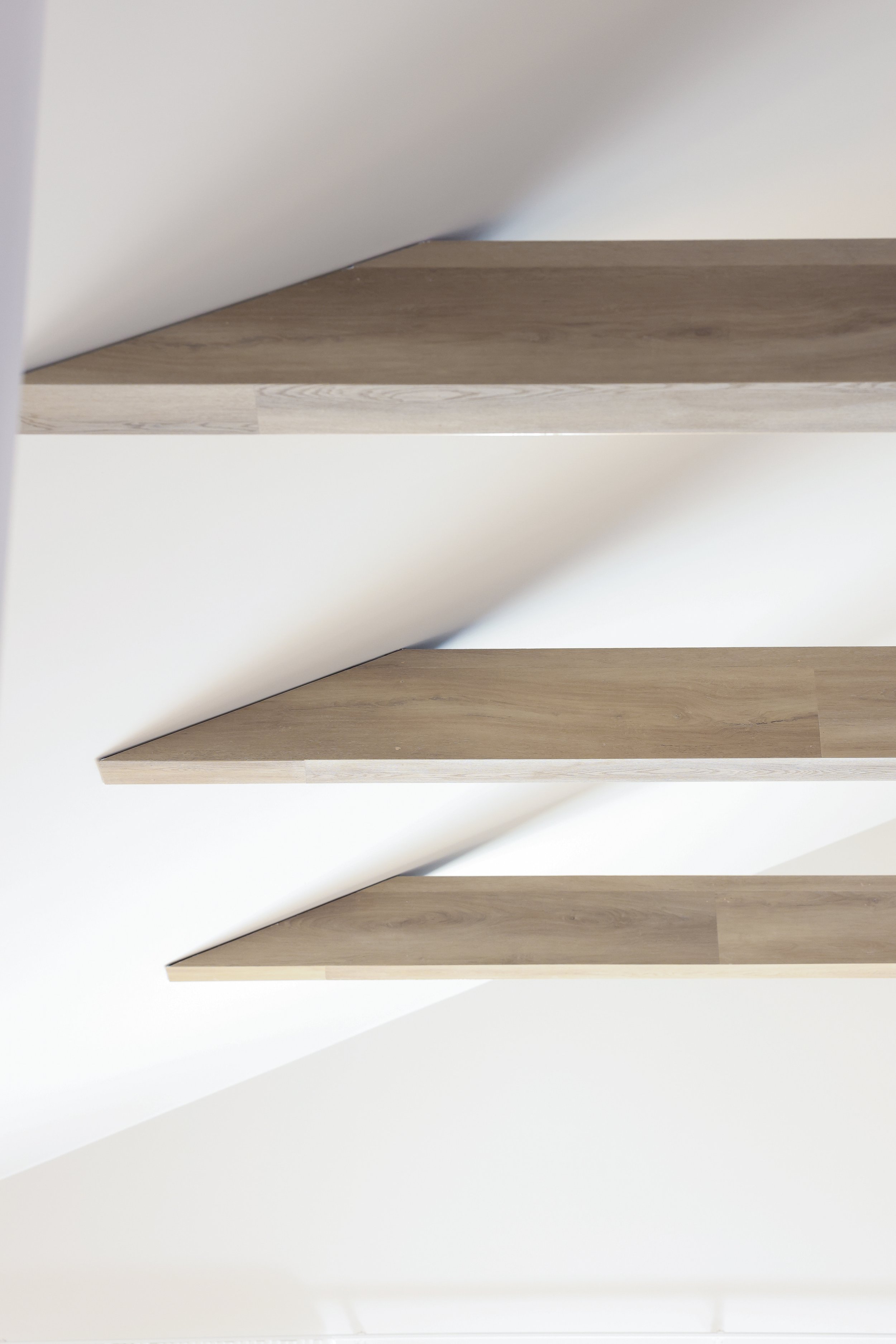 Three shelves mounted on a white wall with wooden textures.