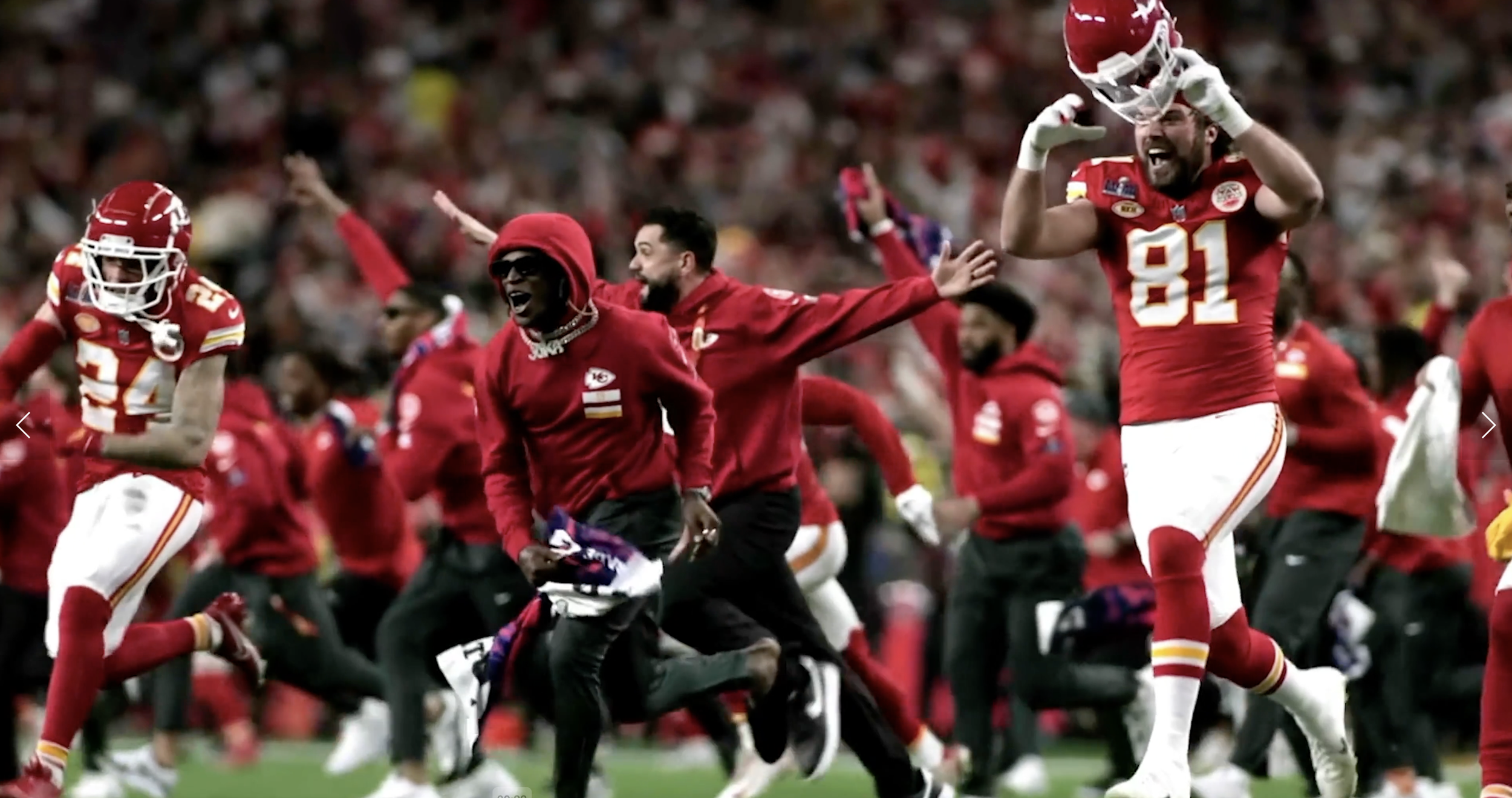 Celebrating Kansas City Chiefs football players and fans on the field, with one player holding his helmet and others cheering.