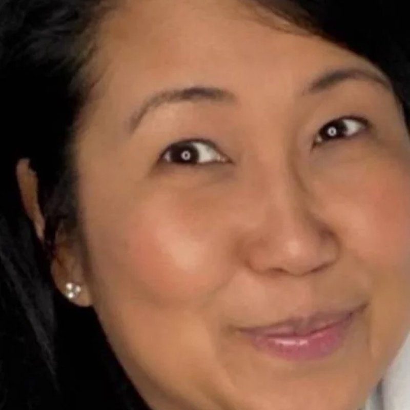 Close-up of a woman's face with a subtle smile, wearing pearl earrings.