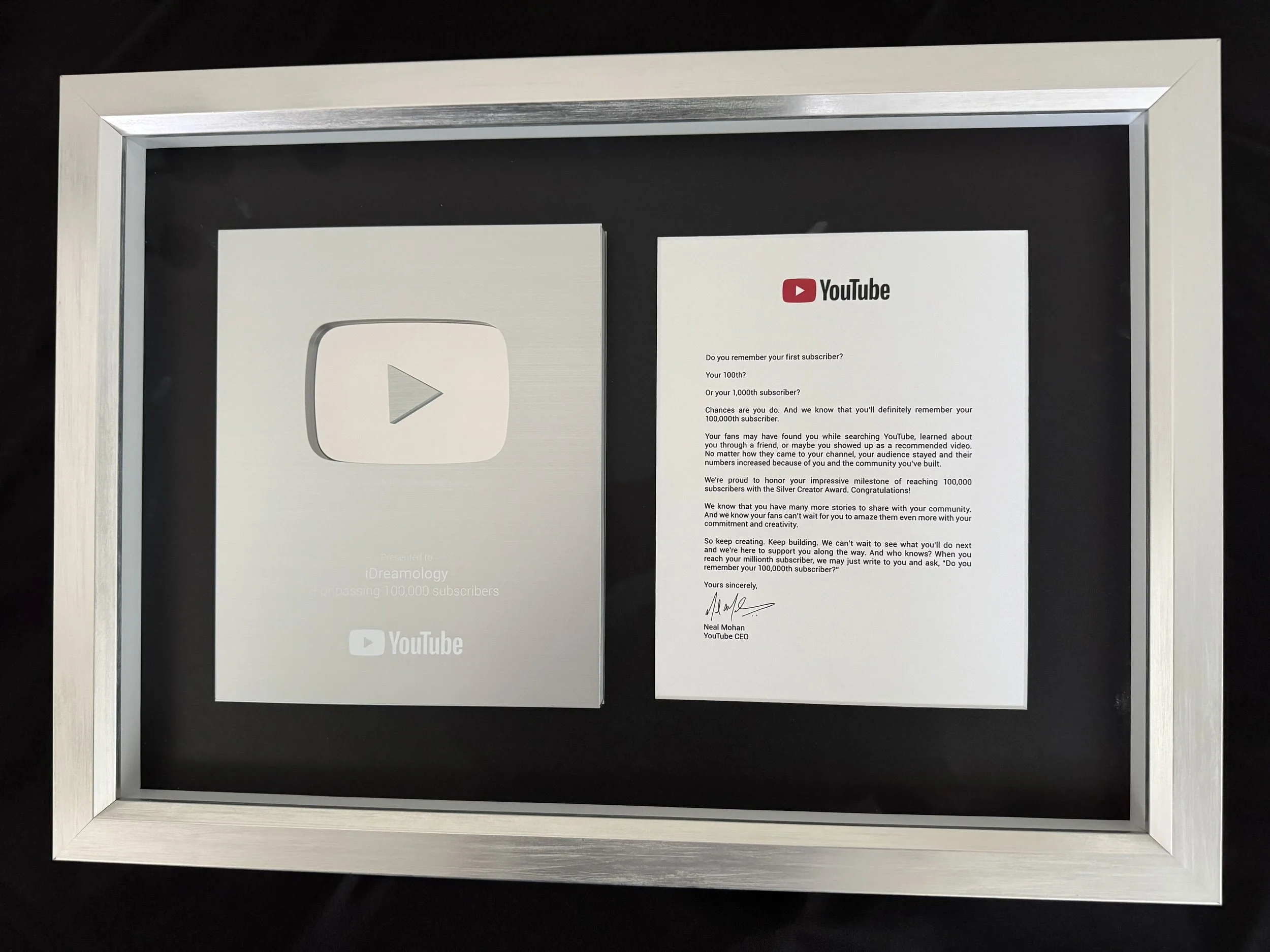 A framed YouTube silver creator award with a letter from YouTube CEO Neal Mohan, congratulating the recipient on reaching 100,000 subscribers.