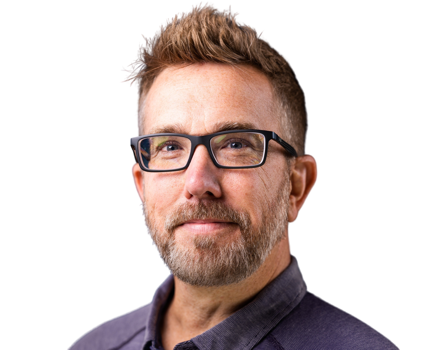 A smiling middle-aged man with glasses, a beard, and short brown hair, wearing a dark shirt.