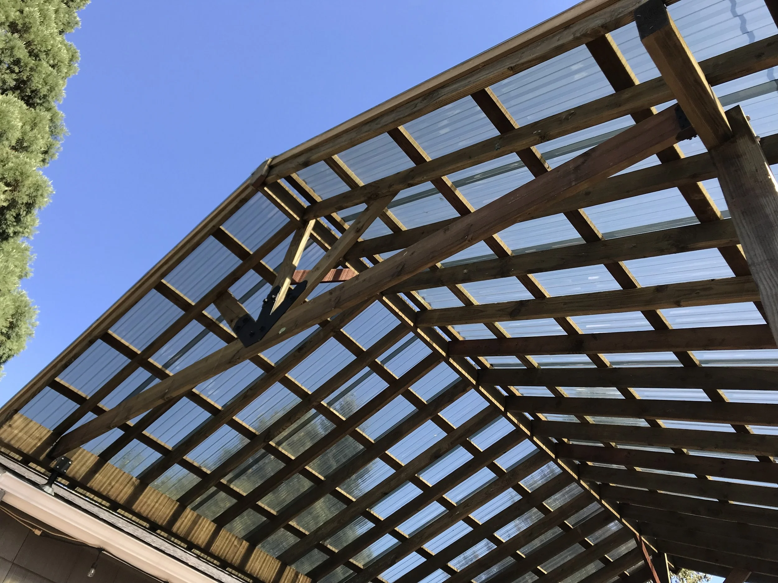 Wooden and metal outdoor structure under a clear blue sky with some green trees in the background.
