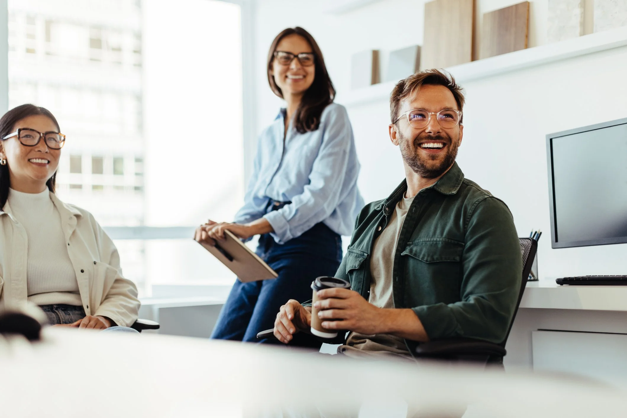 Three people in an office, two women and one man, smiling and talking. The woman on the left wears glasses and a cream-colored shirt, Career Studio | Your next step could change everything. Practical career planning resources.
