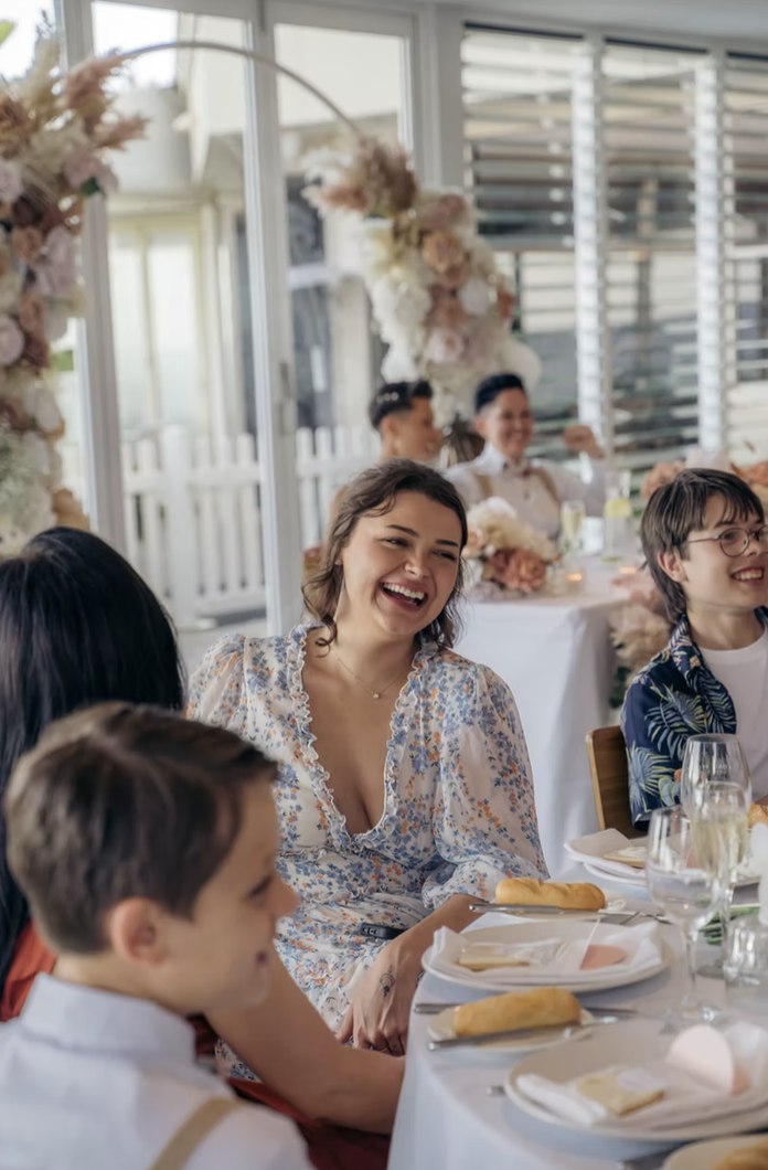 People enjoying a meal and laughing at a decorated dining table during a celebration.