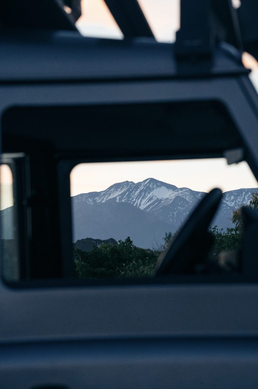 Snow-capped mountain viewed through a vehicle window.