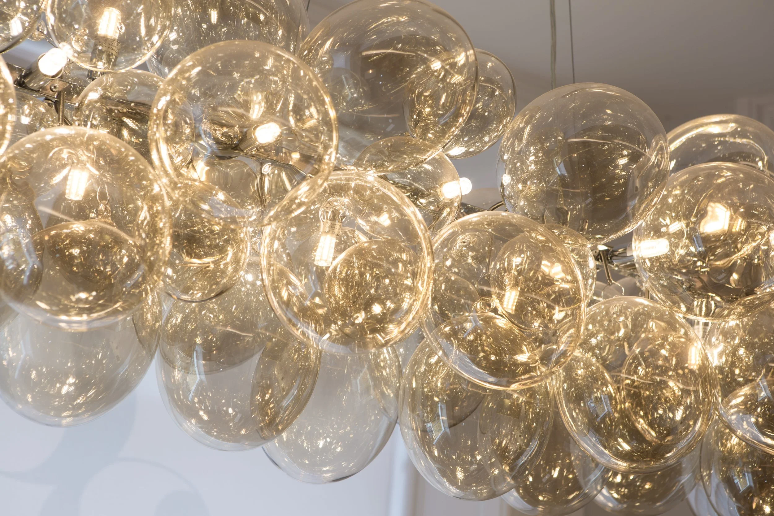 A chandelier made of multiple clear glass spheres with embedded light bulbs, creating a luminous display.