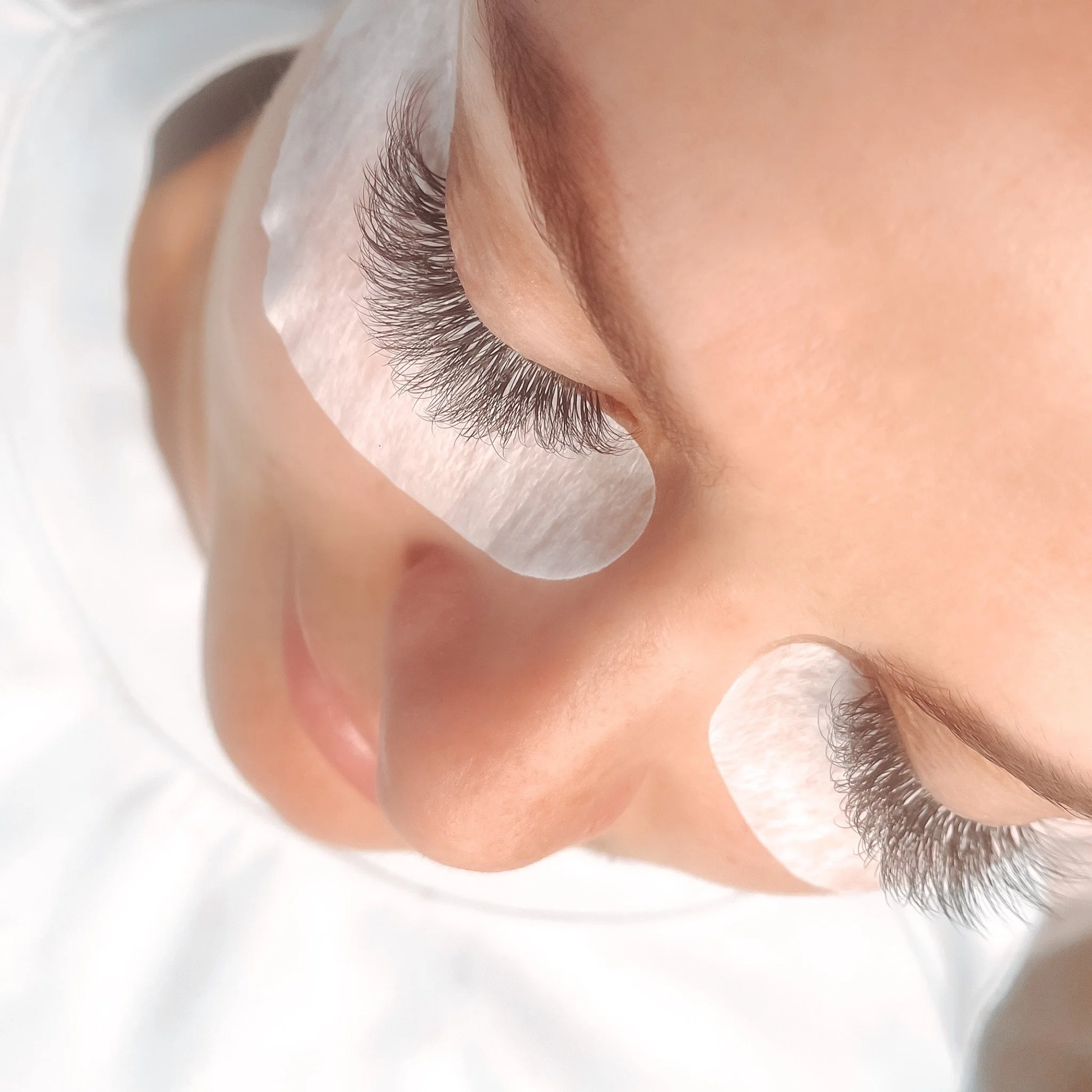 Close-up of a person's eye with long eyelashes and a cosmetic eyelash extension application.