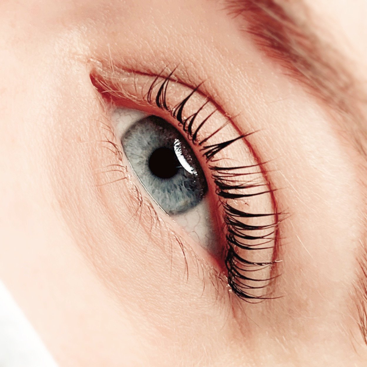 Close-up of a blue eye with long, dark eyelashes and light skin surrounding it.