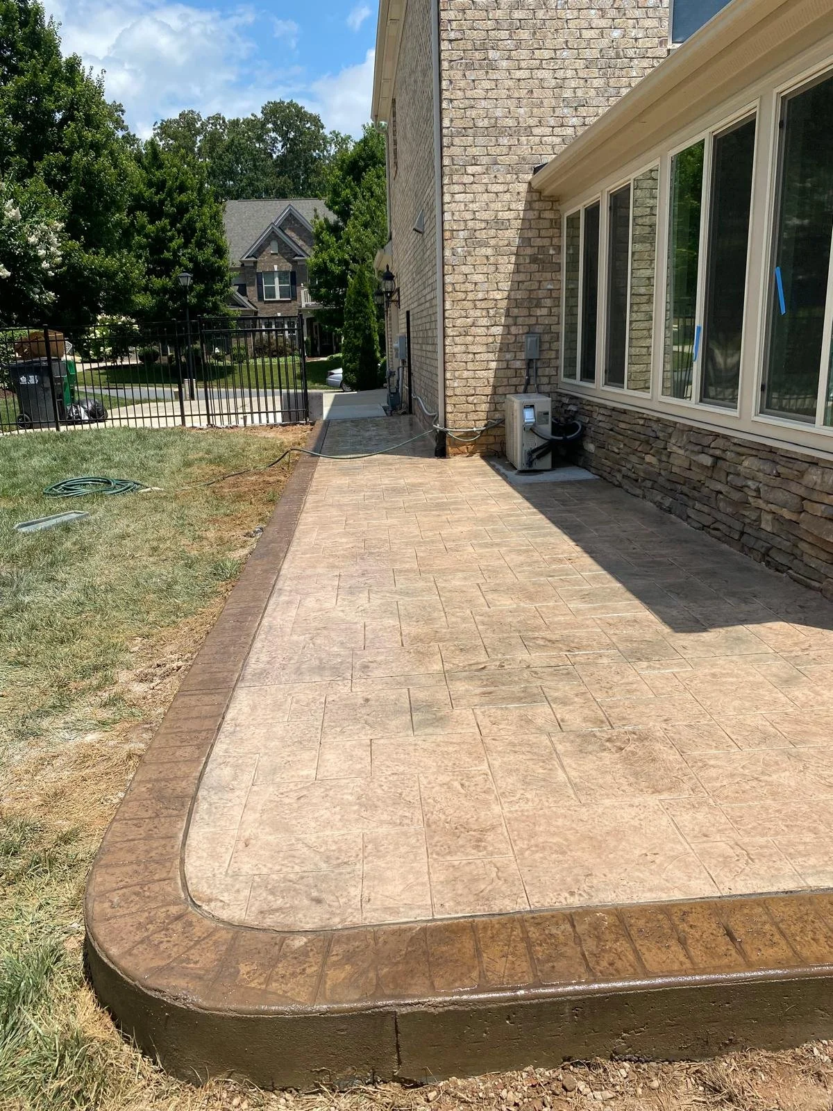 Stamped concrete patio in Charlotte, NC featuring a custom decorative design with textured stone pattern and natural color tones. The finished surface is sealed for durability and weather resistance, creating a stylish outdoor living space that enhan