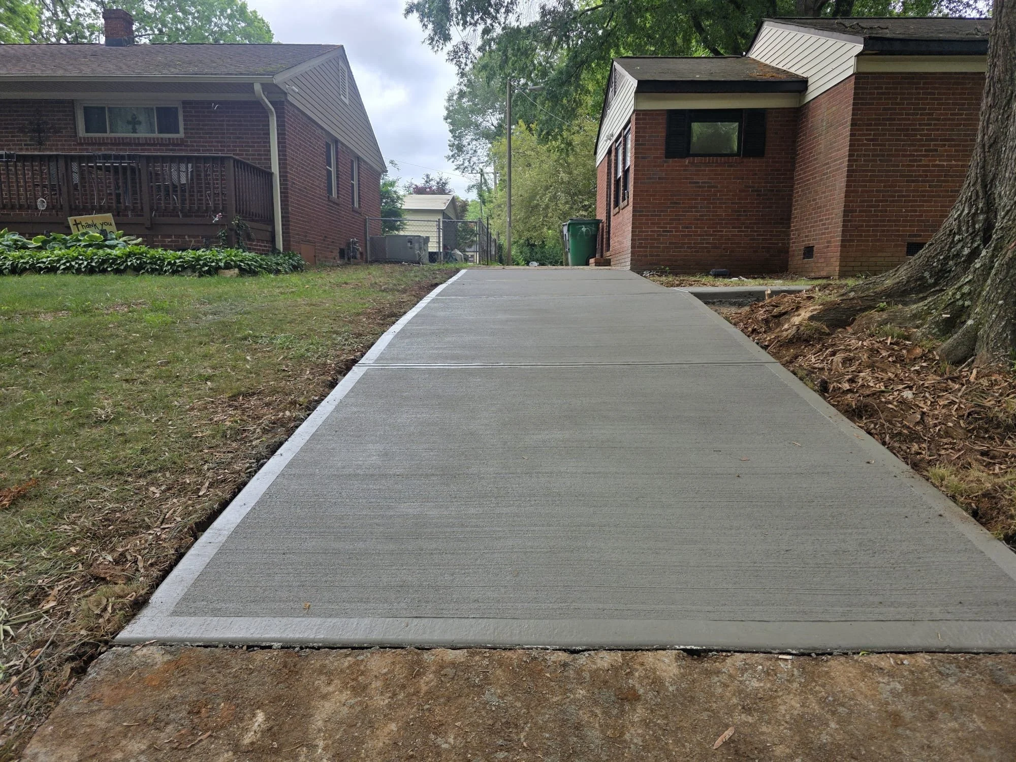 Freshly poured broom-finish concrete driveway with sidewalk in a residential community.