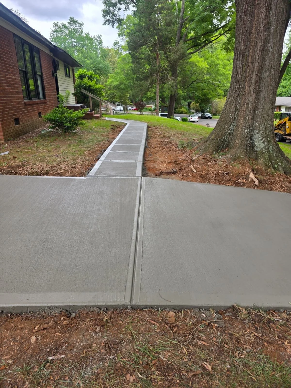 Driveway and sidewalk renovation at an older residential home, fully restored with new concrete installation. The project features a freshly poured driveway and walkway with a smooth, clean finish that replaces worn, aged surfaces. The upgraded concr