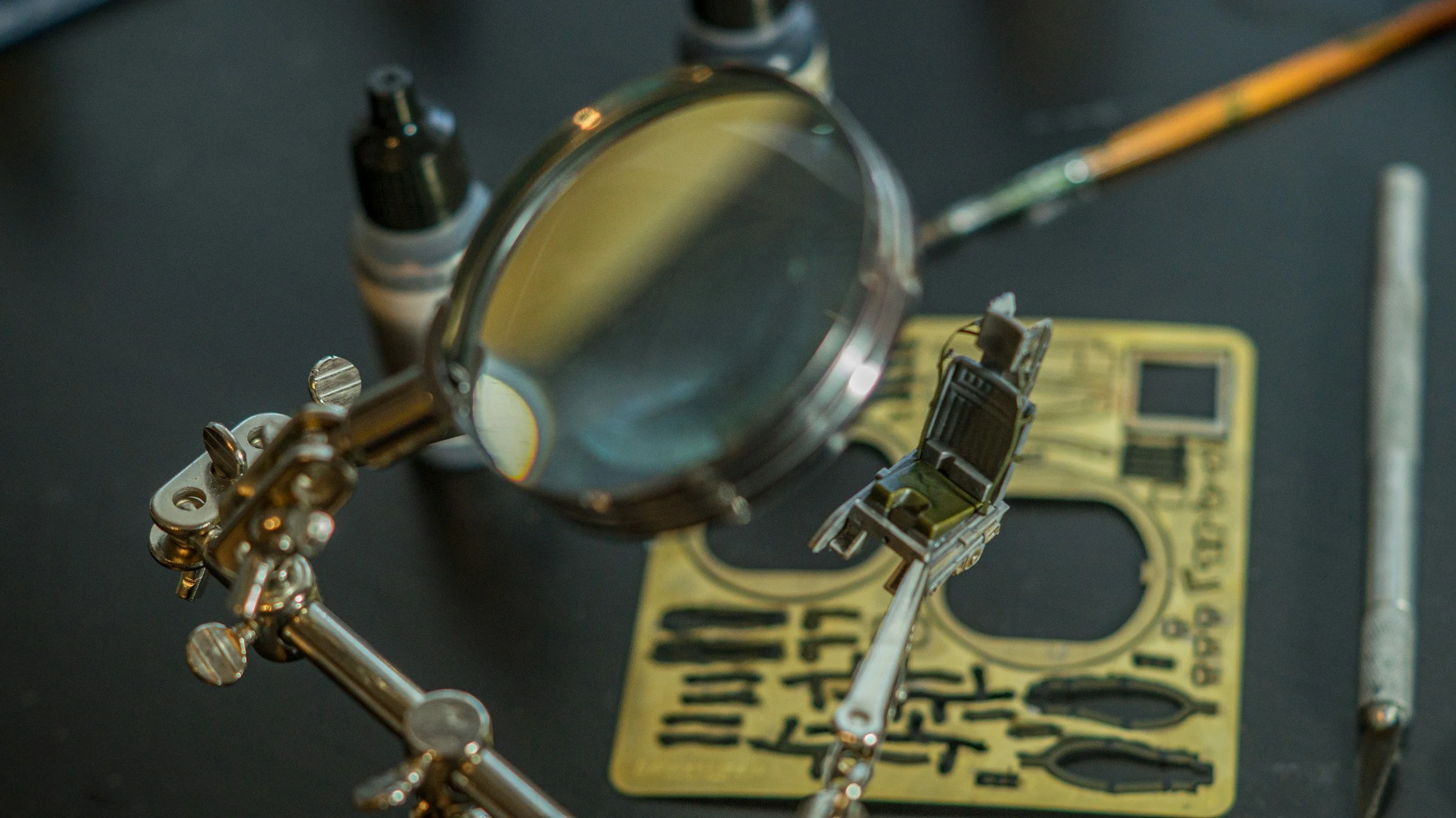 Close-up of a magnifying glass focusing on a small firearm, with a yellow caution sign in the background.