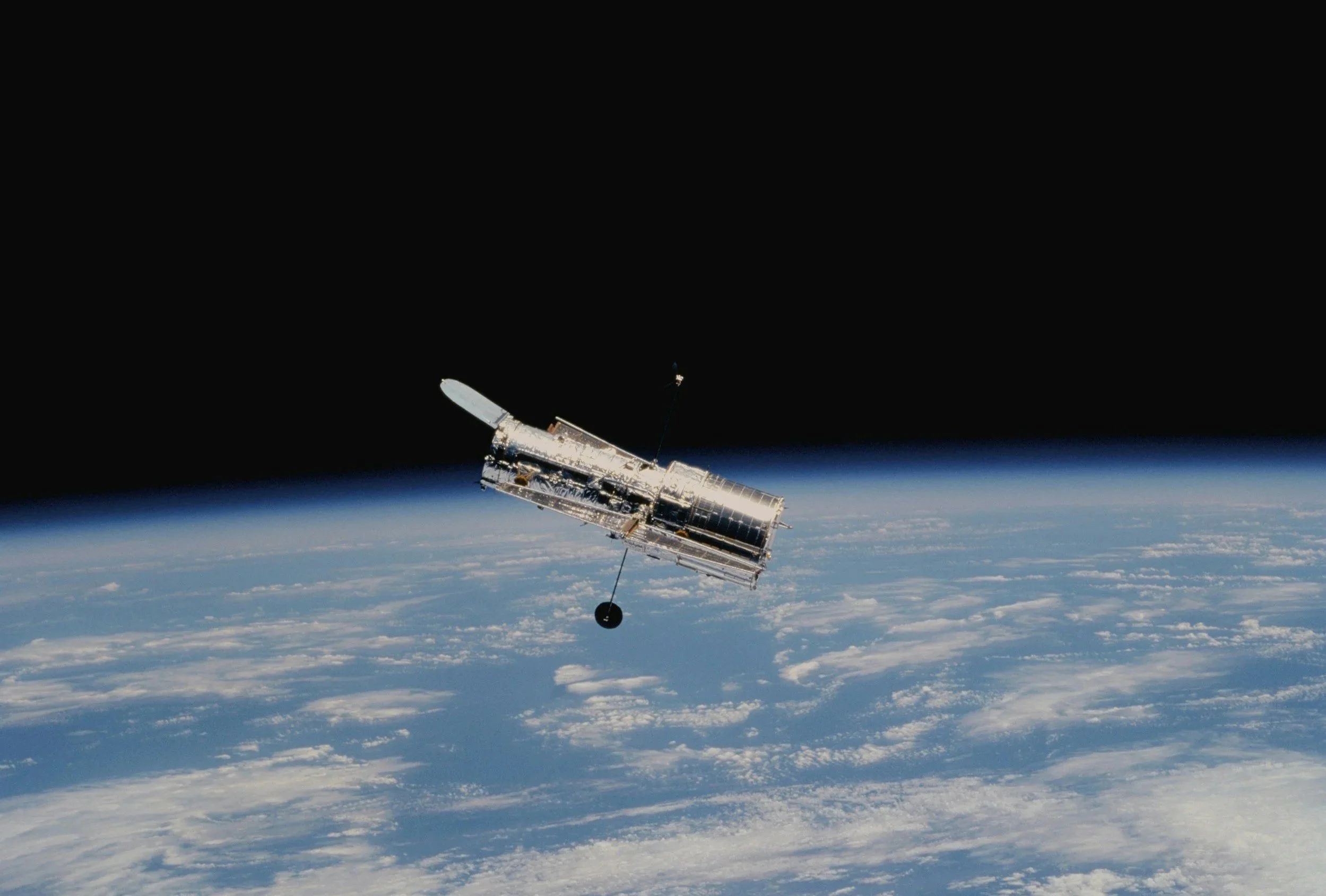 An astronaut's spacecraft is floating above Earth space with the horizon visible, and space in the background.