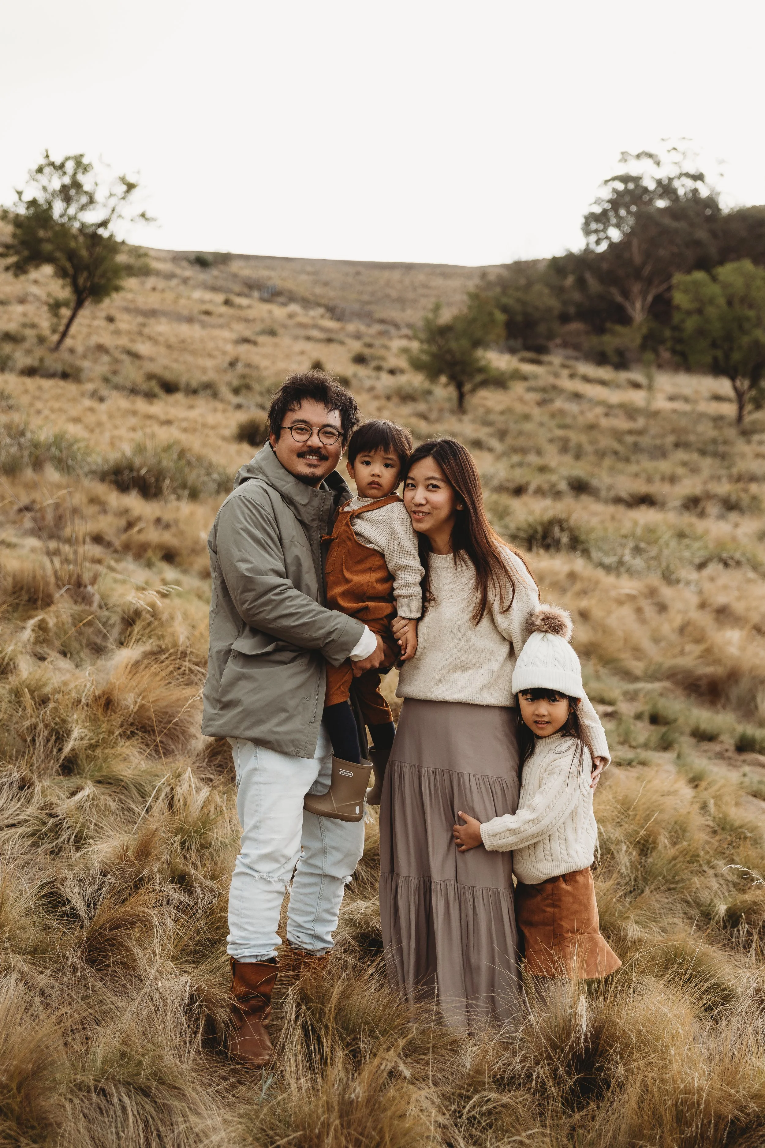Young Family standing in field dressed in winter layers