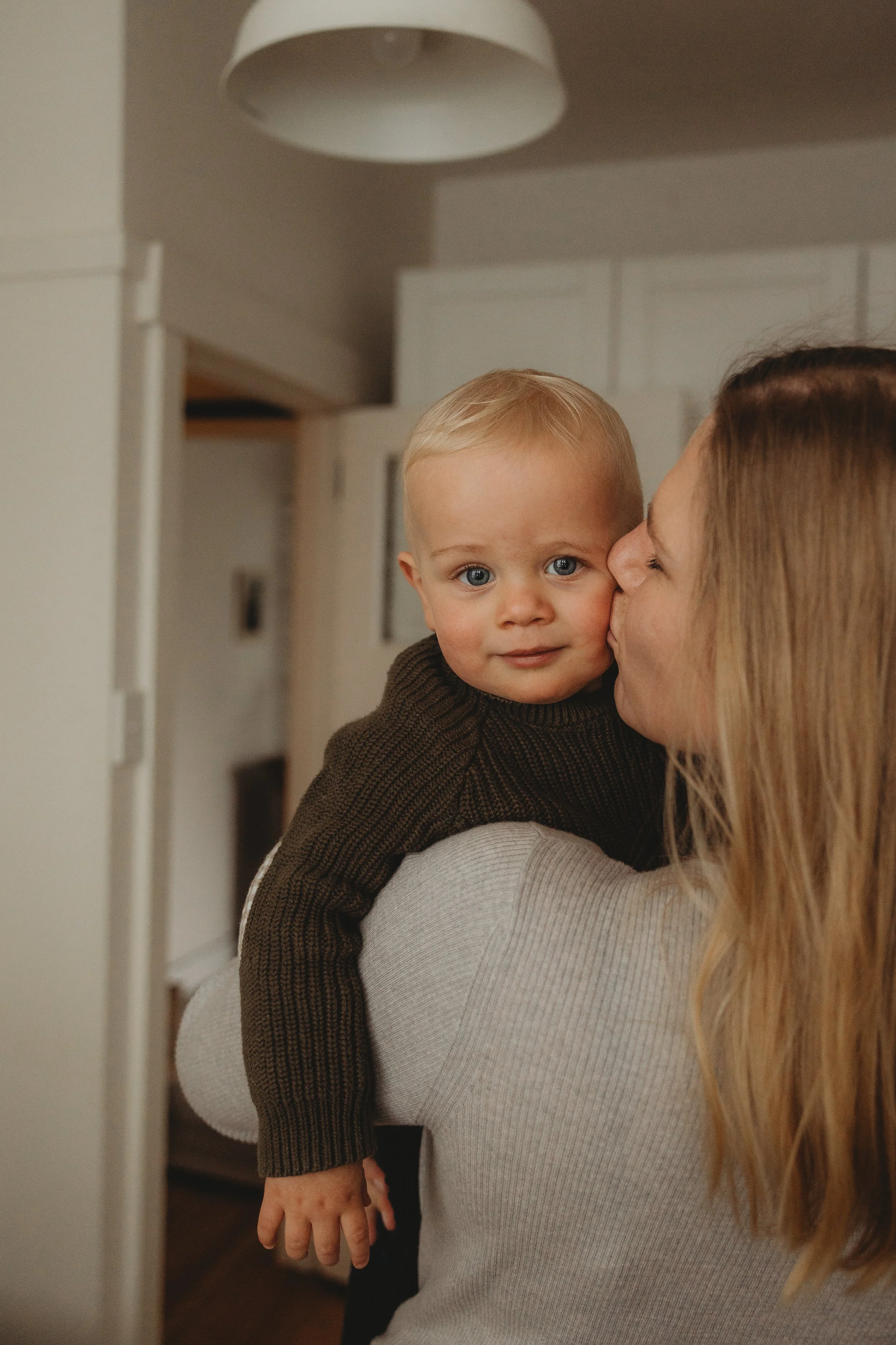 Mother holding young toddler giving a kiss on the cheek