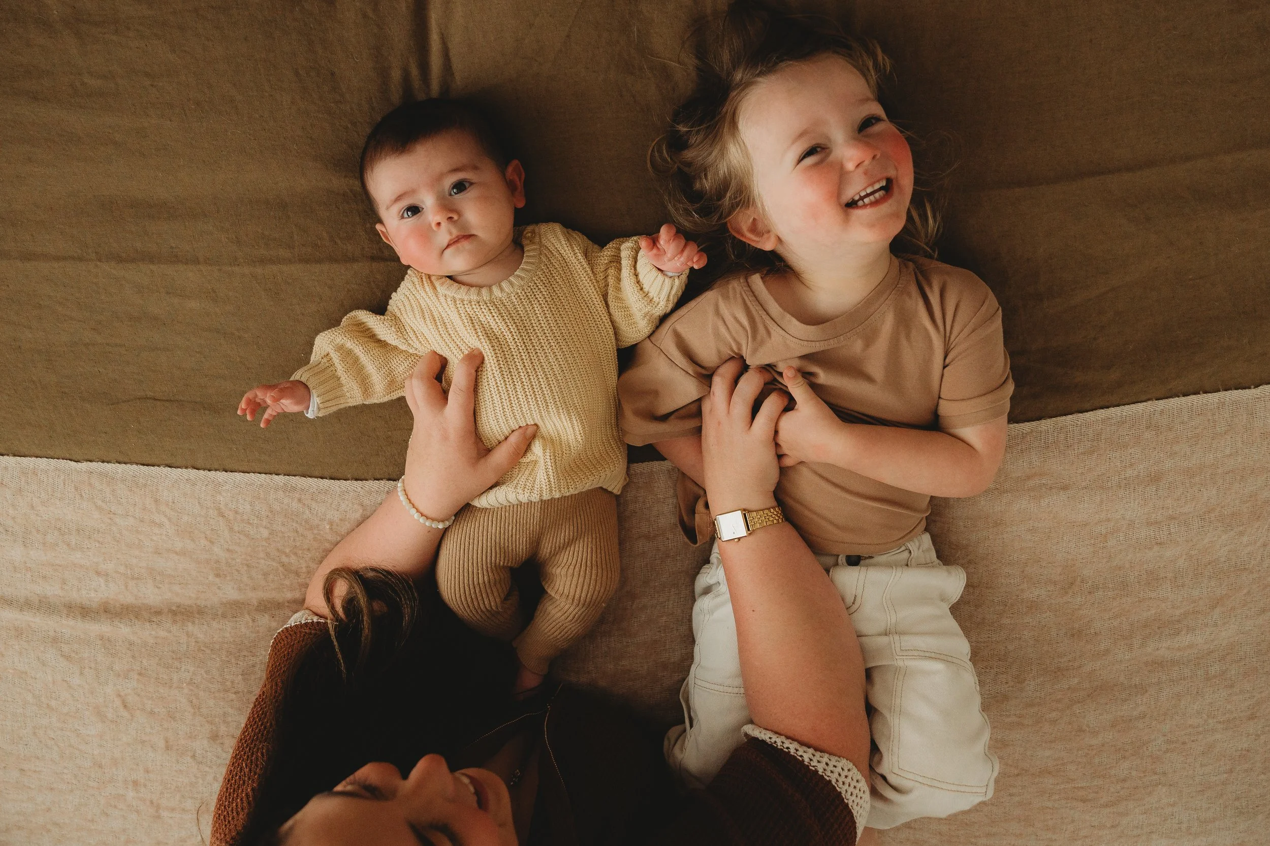 two young children being ticked on bed