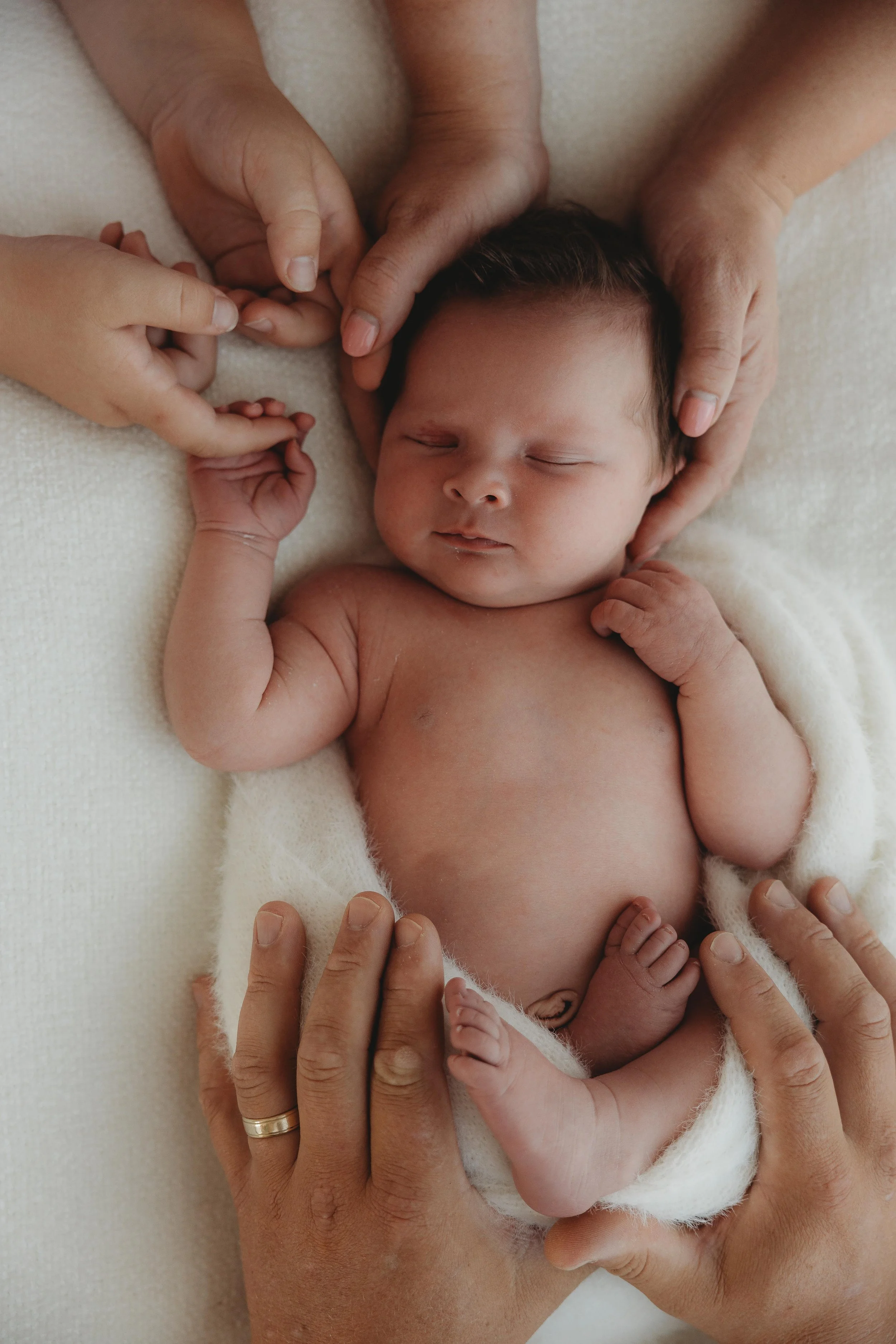 Newborn baby being held by family on bean chair