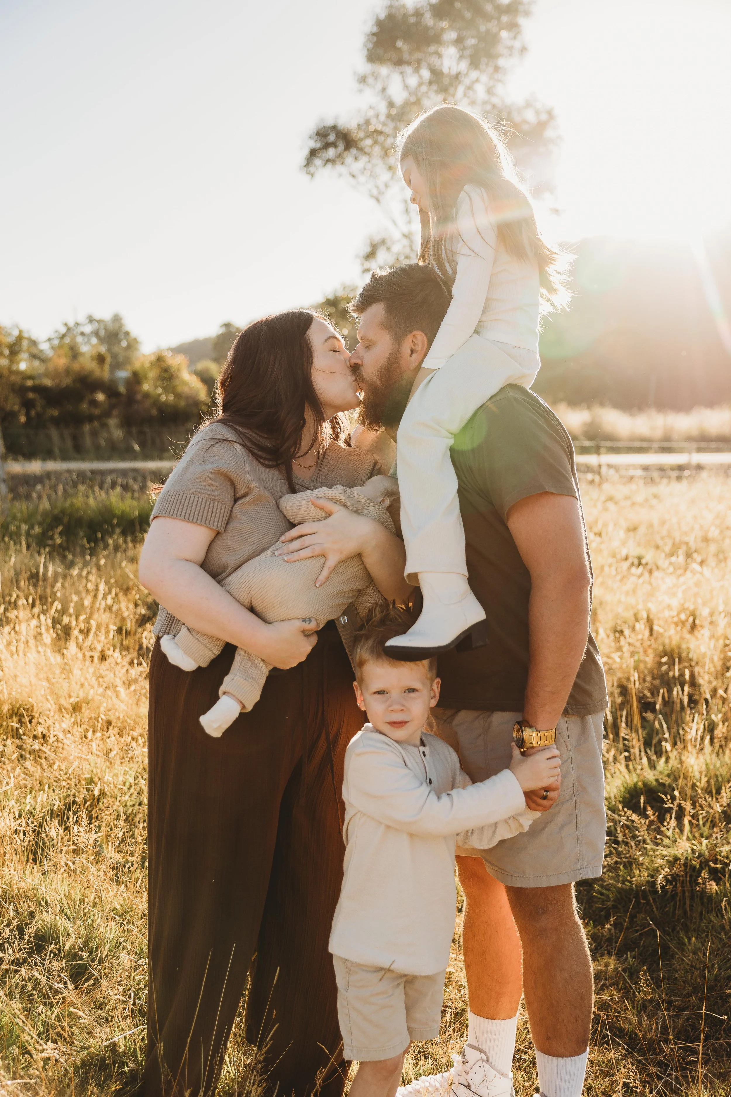 family with newborn baby in a field all together