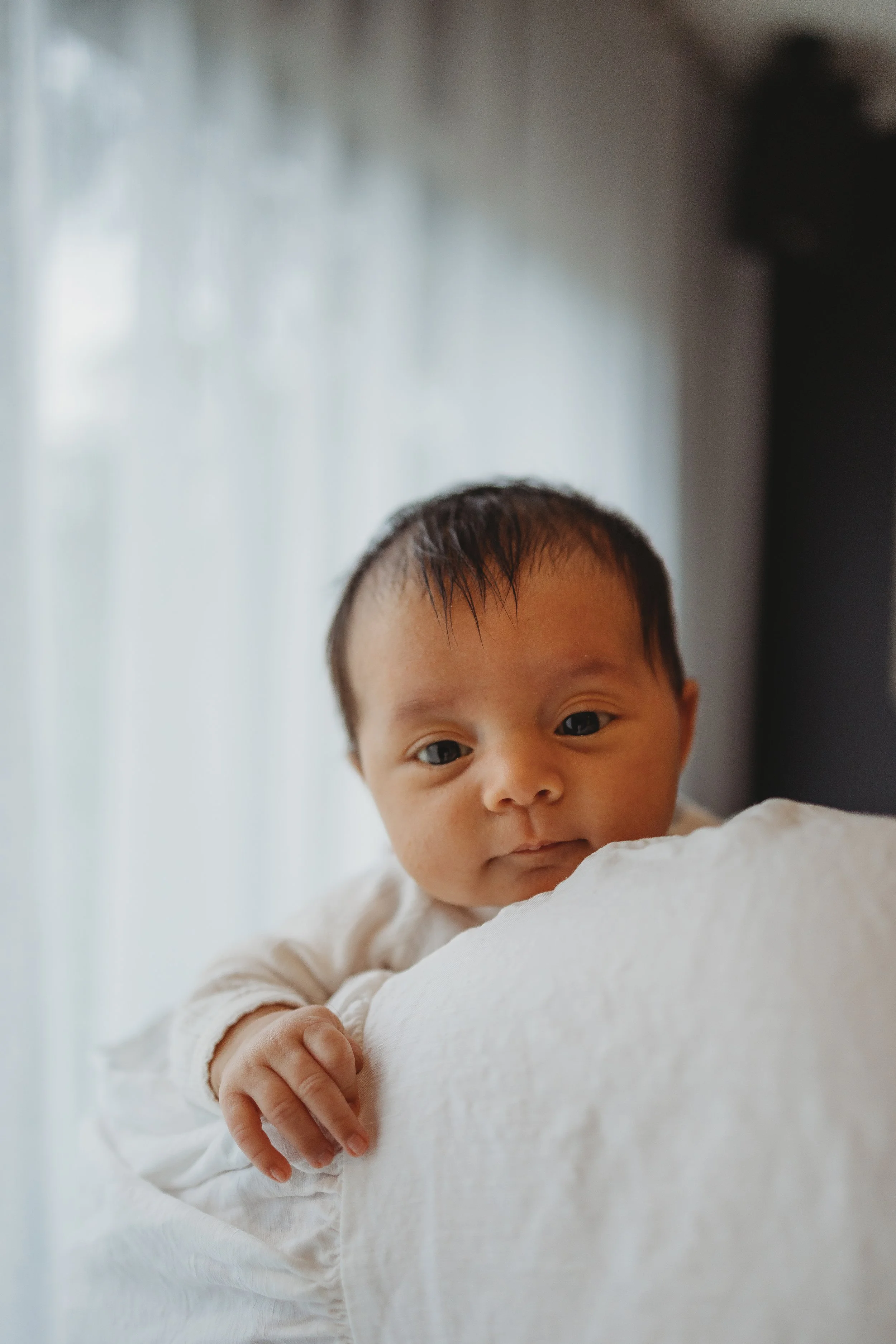 baby looking over parents shoulder at the camera
