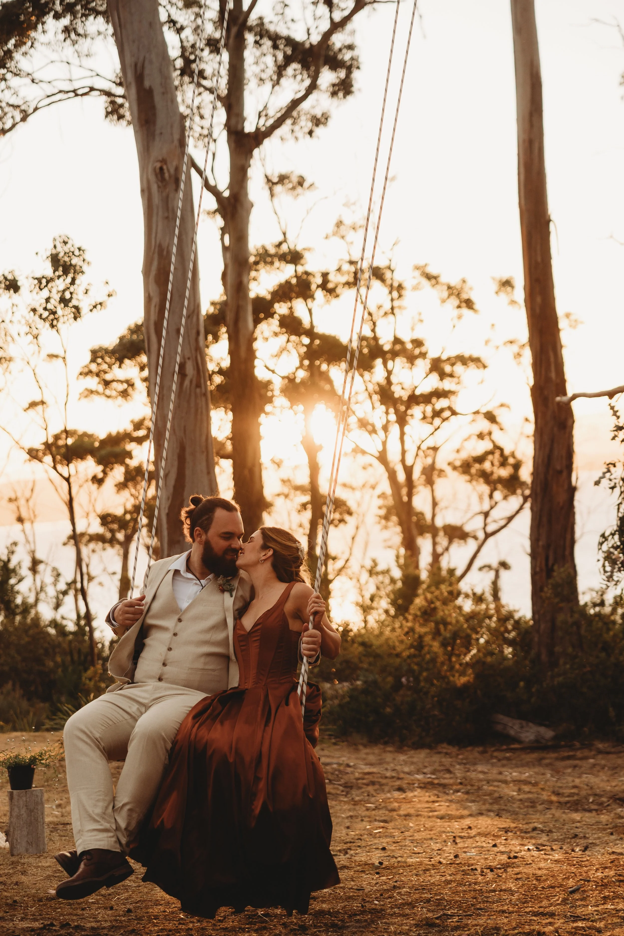bride and groom on swing at sunset