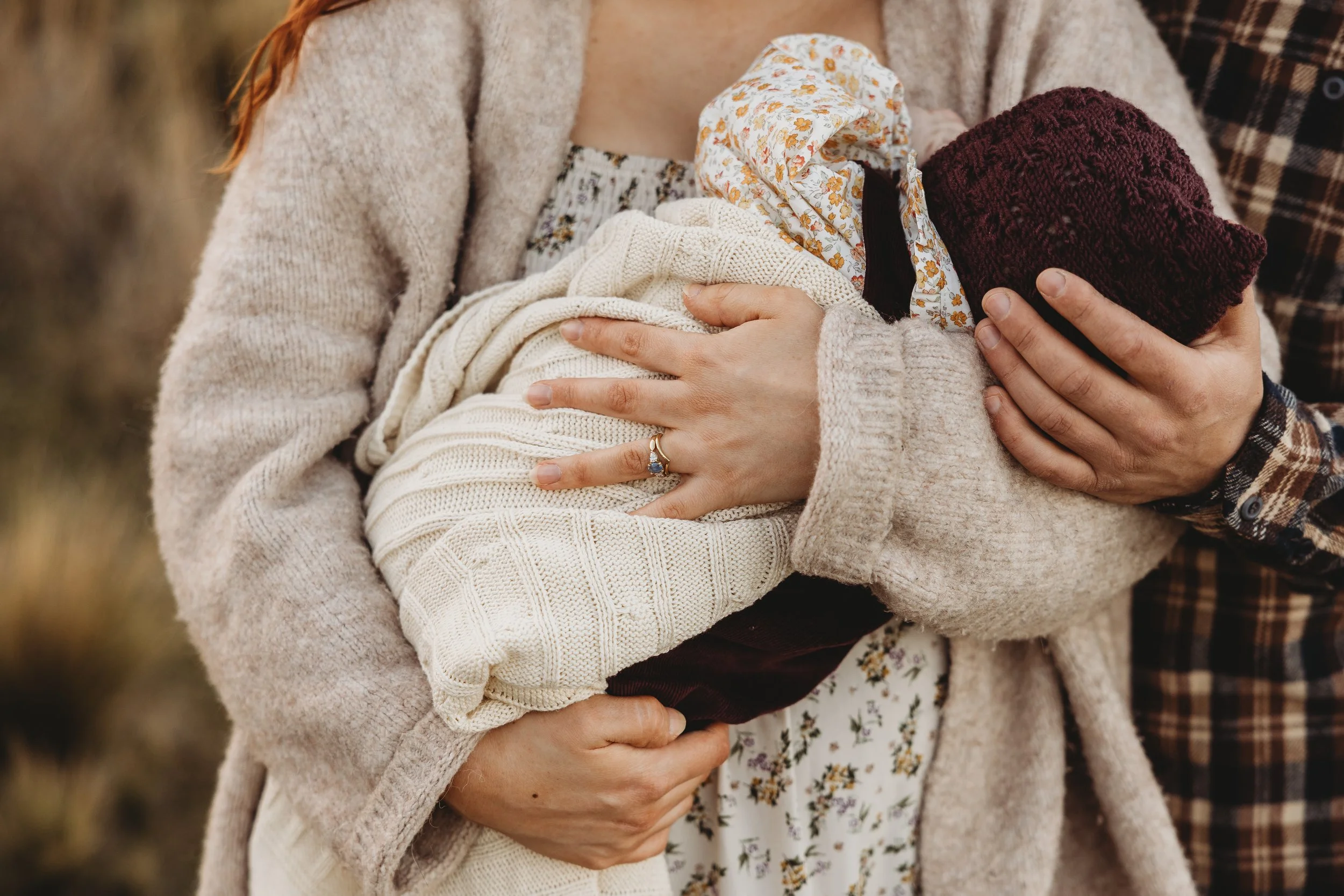 family dressed in layers cradling their new baby 