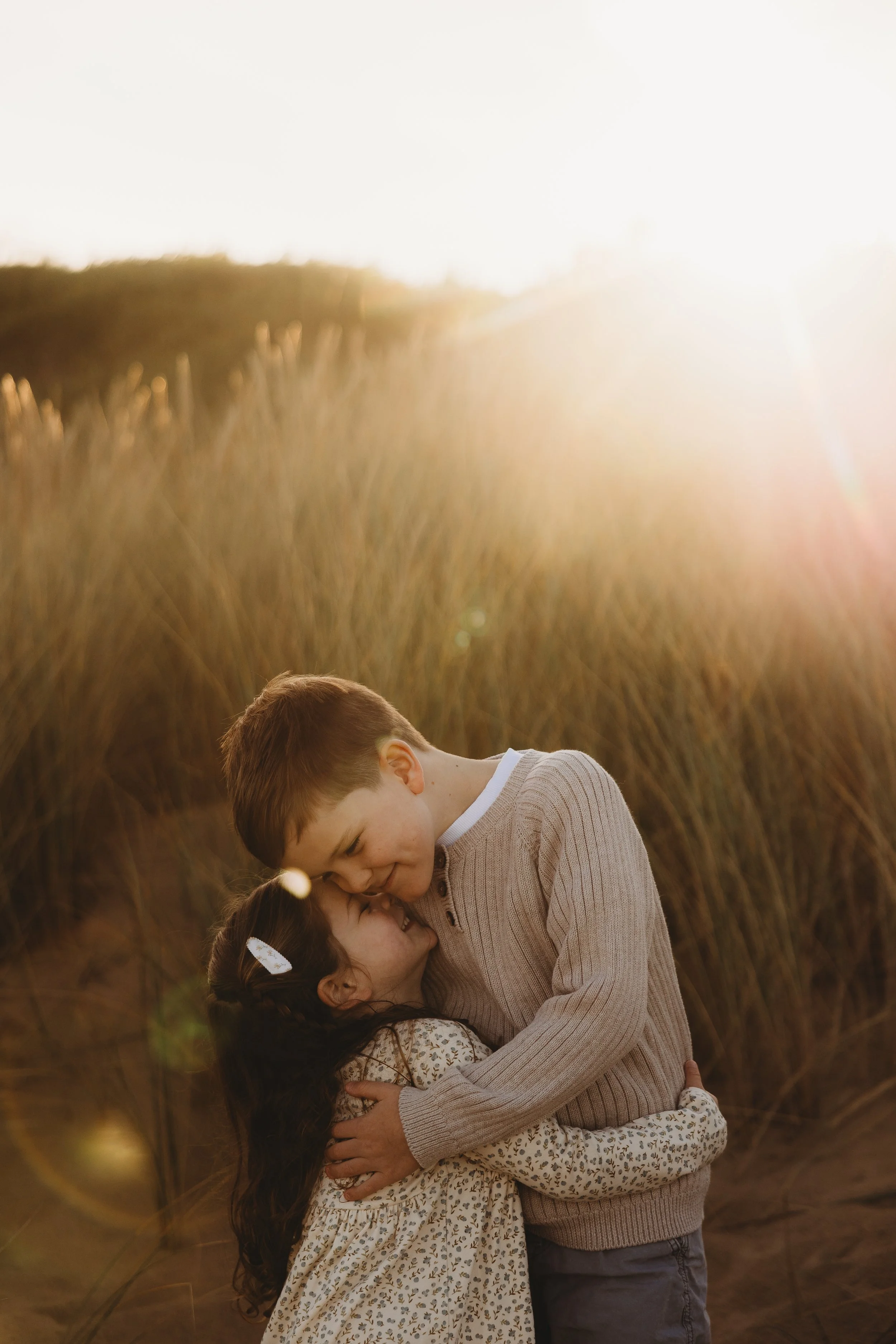 Siblings hugging at the beach at golden hour