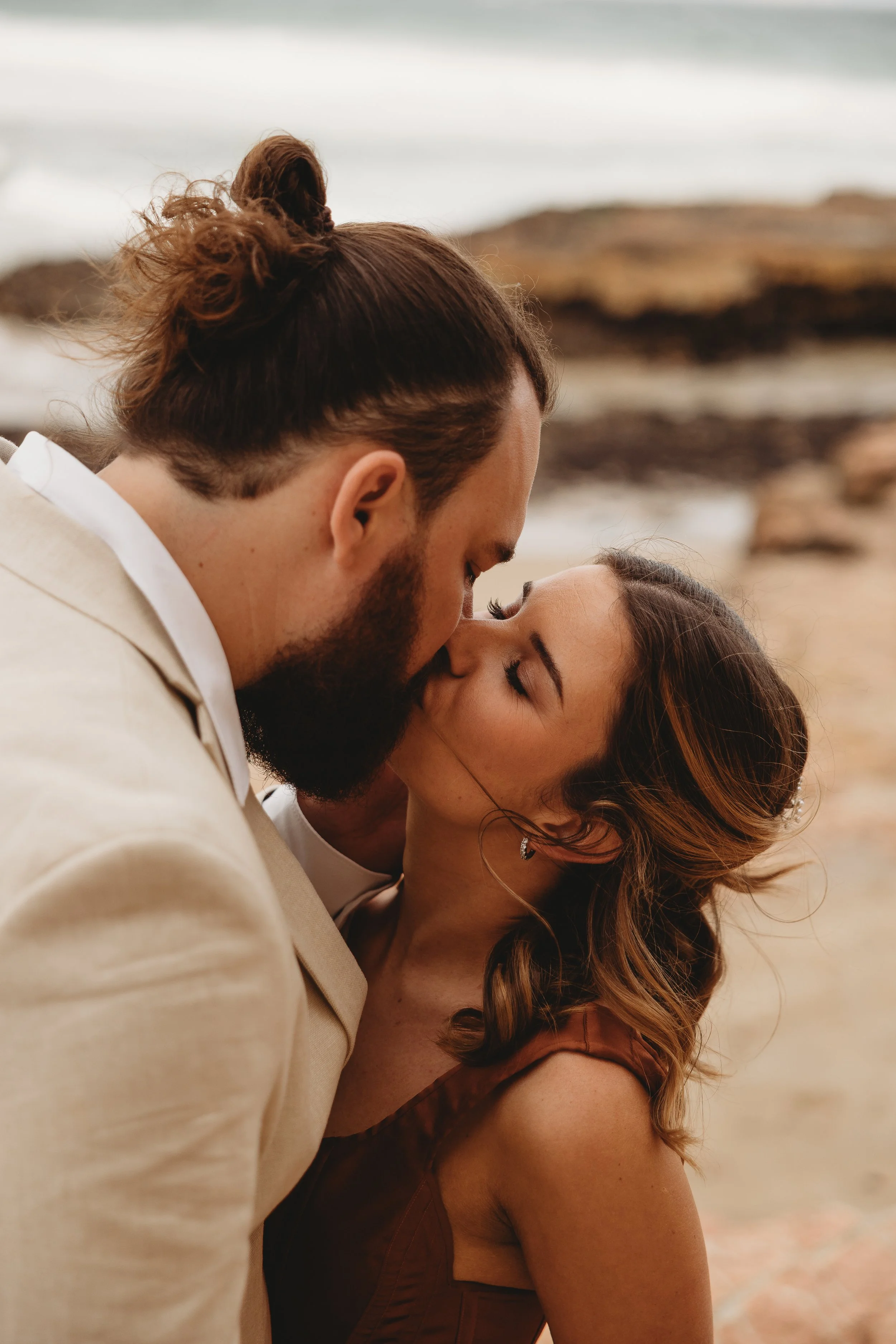 bride and groom kissing on beach