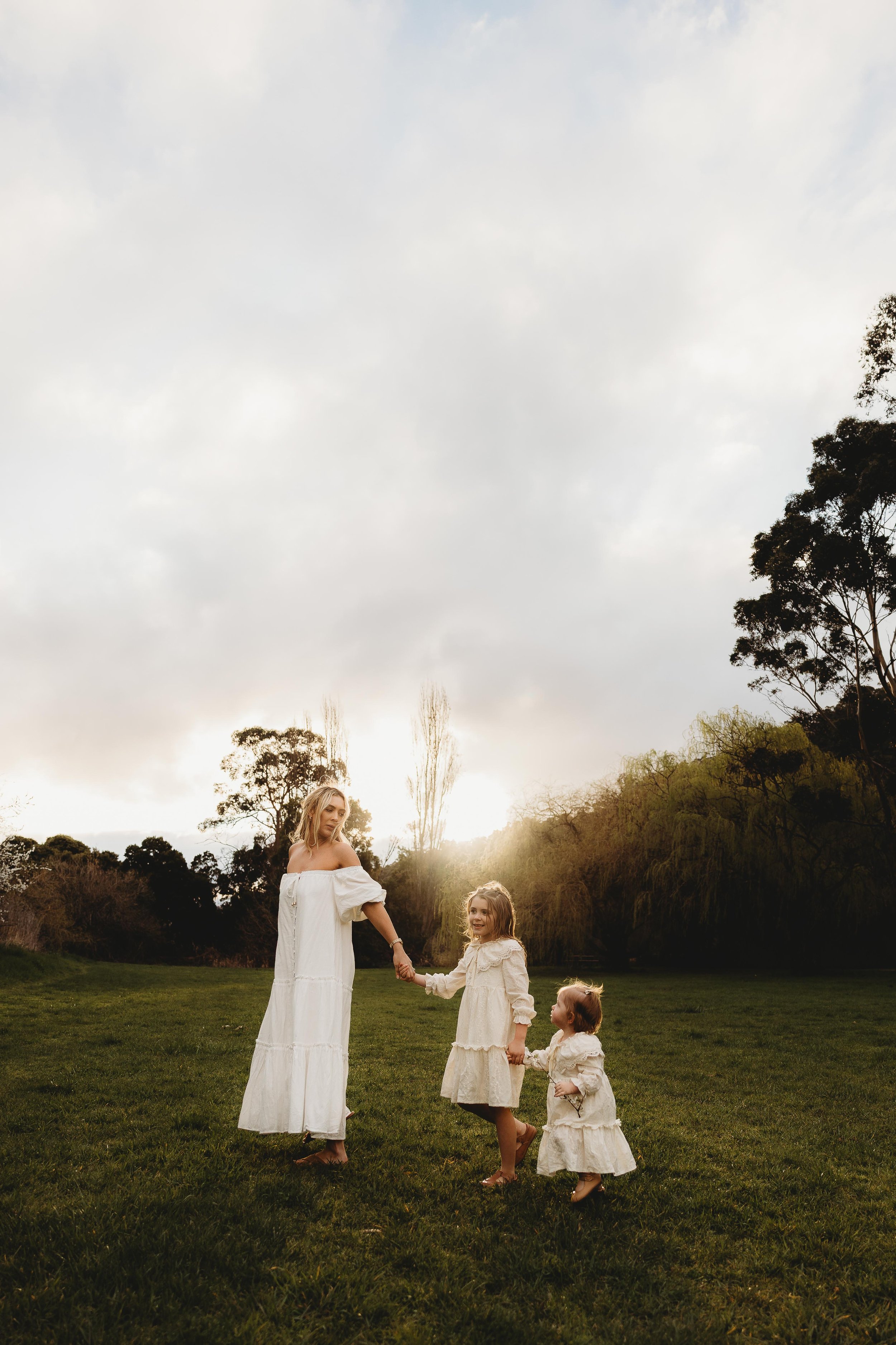mum holding daughters hands as she walks along